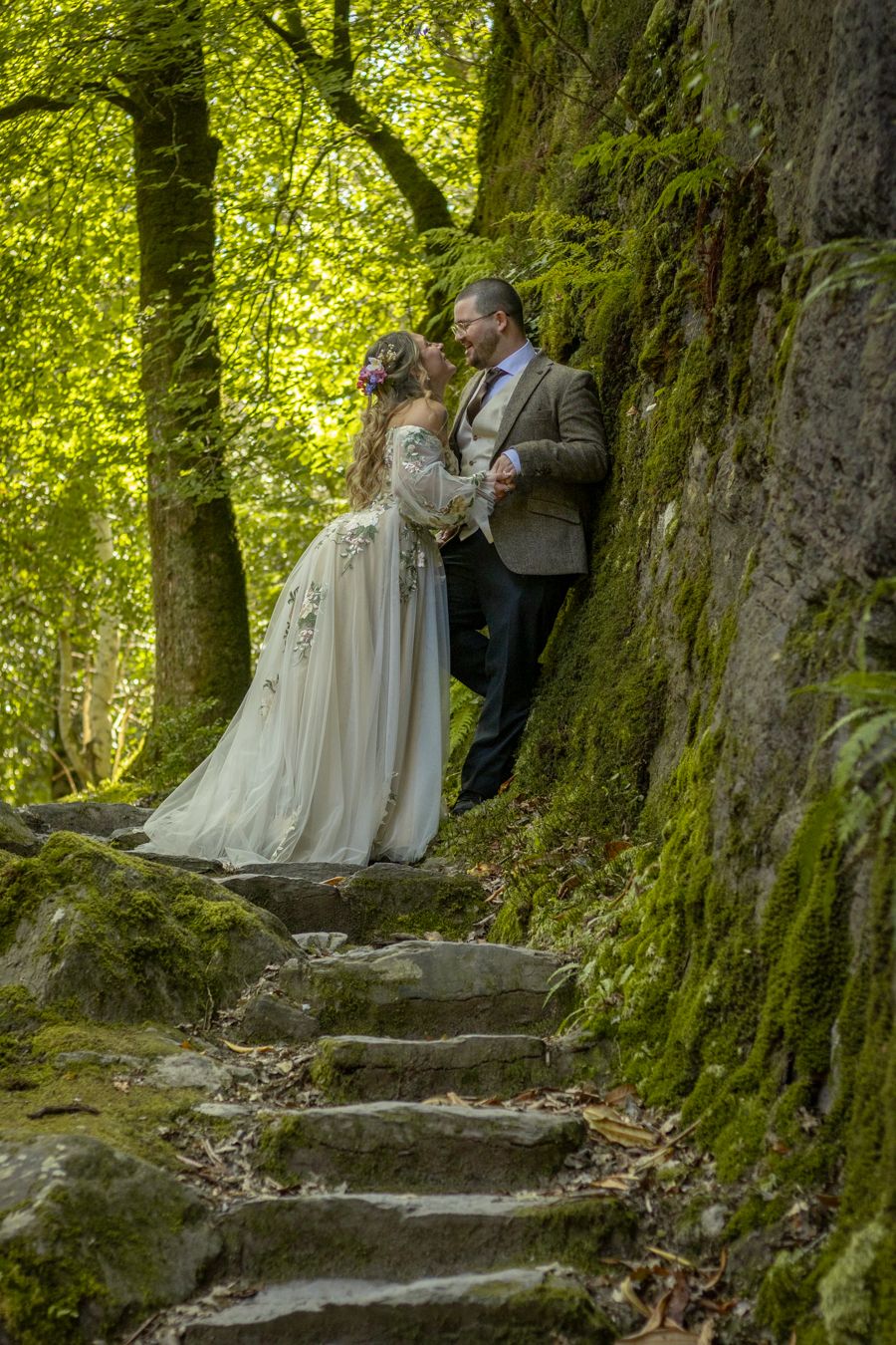 Couple leaning against a moss wall during a handfasting elopement photoshoot