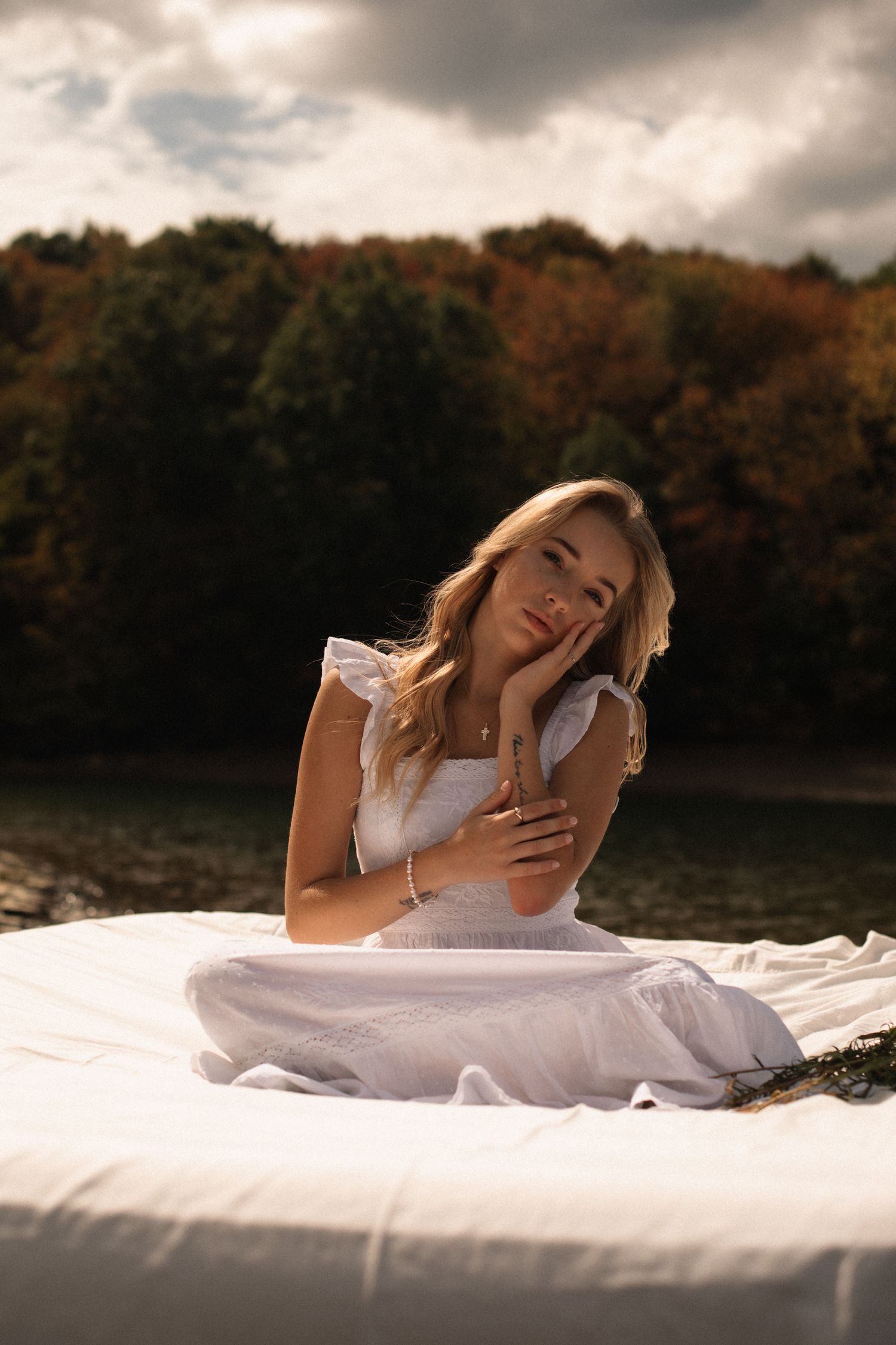 A dreamy outdoor photo session with a white dress against an autumn backdrop by a lake.