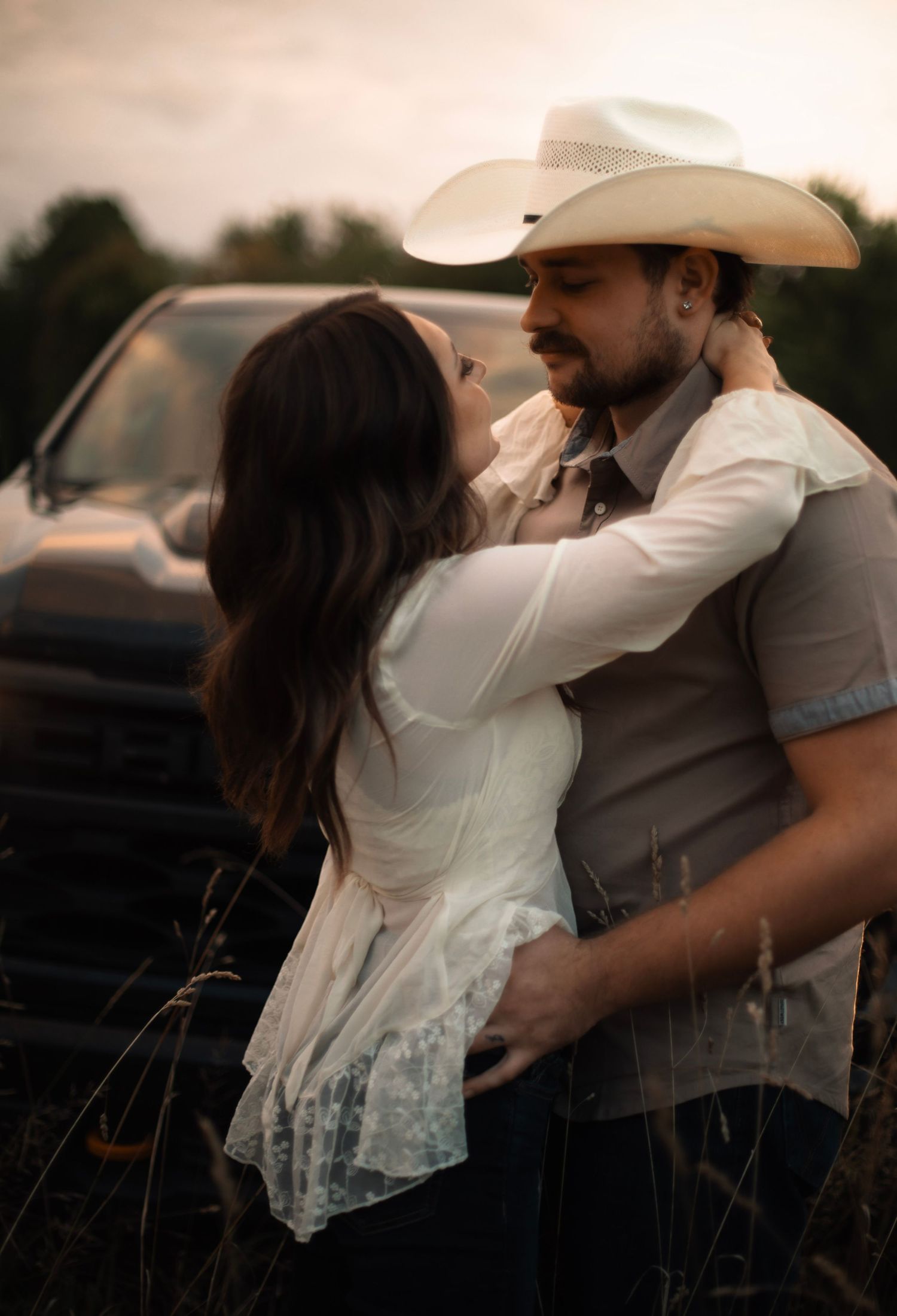 A sequence of sunset photos capturing tender moments between a couple in country western outfits.