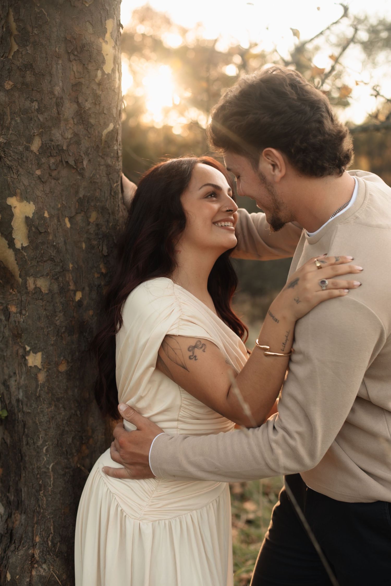 A romantic couple shares tender moments in a sunlit outdoor setting during a golden hour photoshoot.