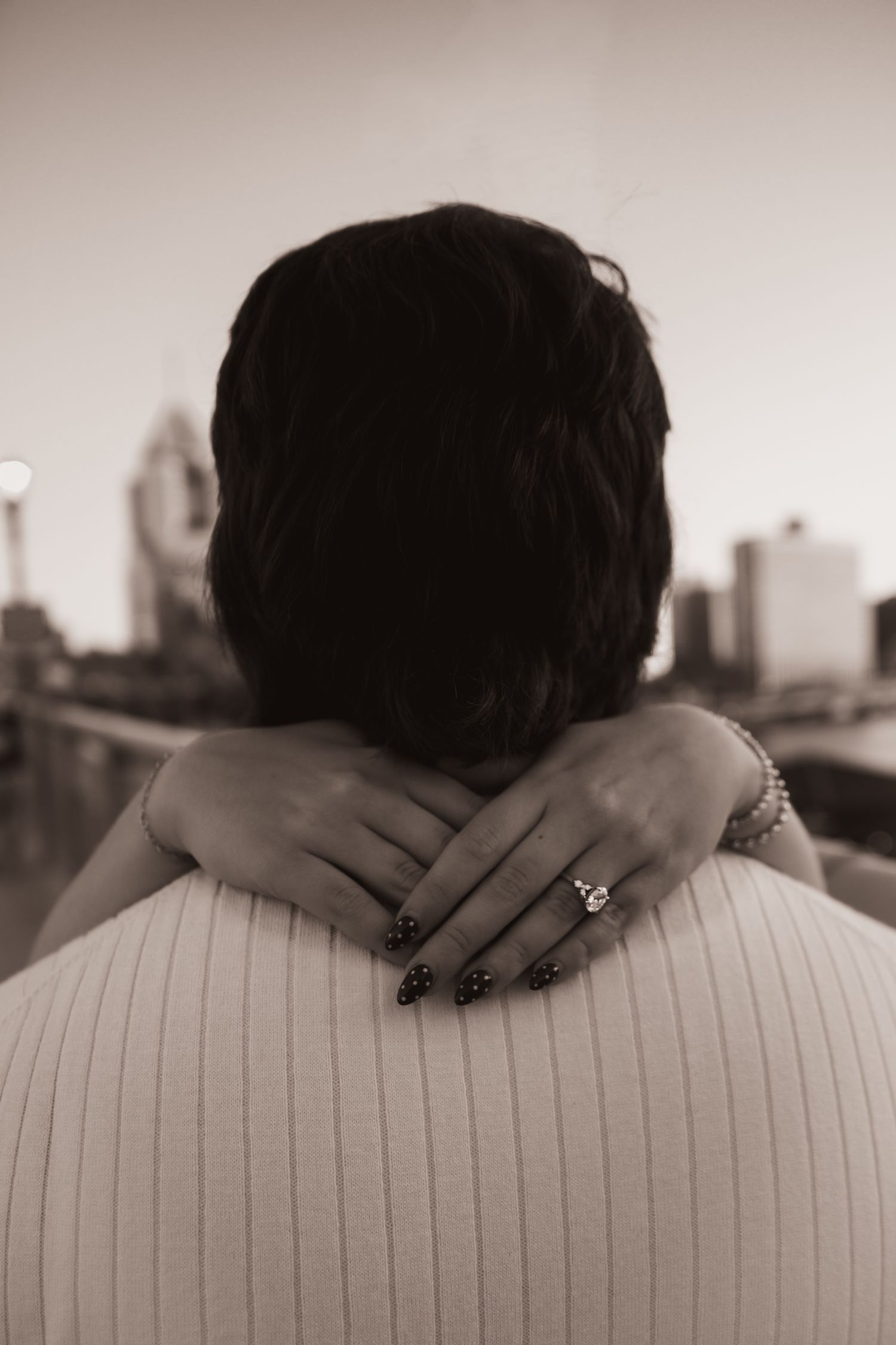 A series of black and white photos showing hands gently placed on the back of a person wearing a ribbed sweater.