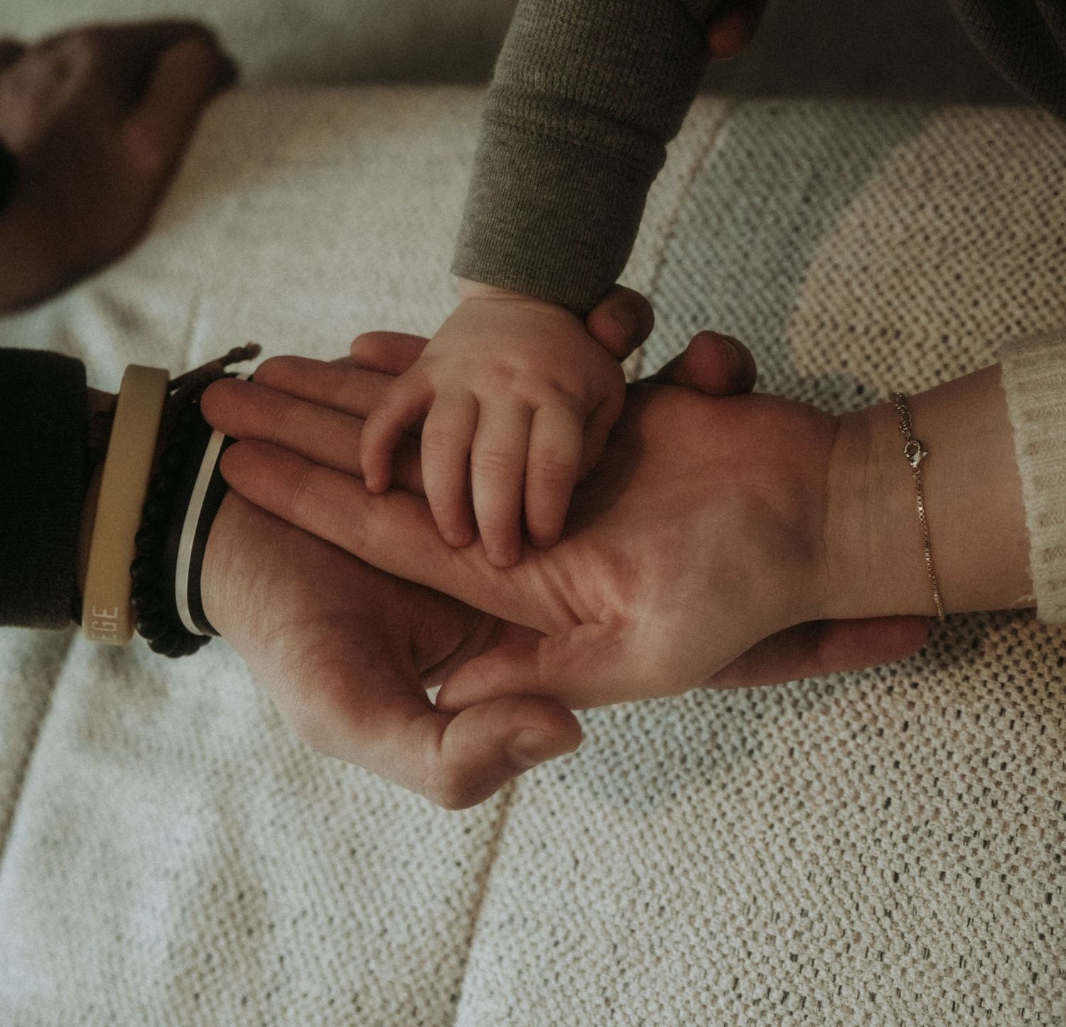 Close-up sequence showing two hands gently holding and touching each other against a textured fabric background.