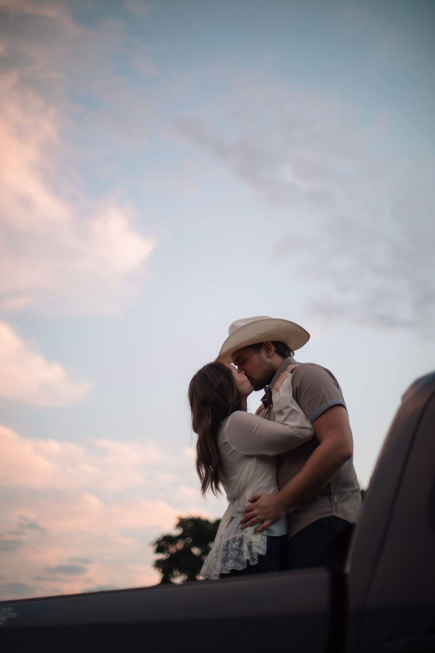 A silhouetted couple shares an intimate moment against a pastel sunset sky.