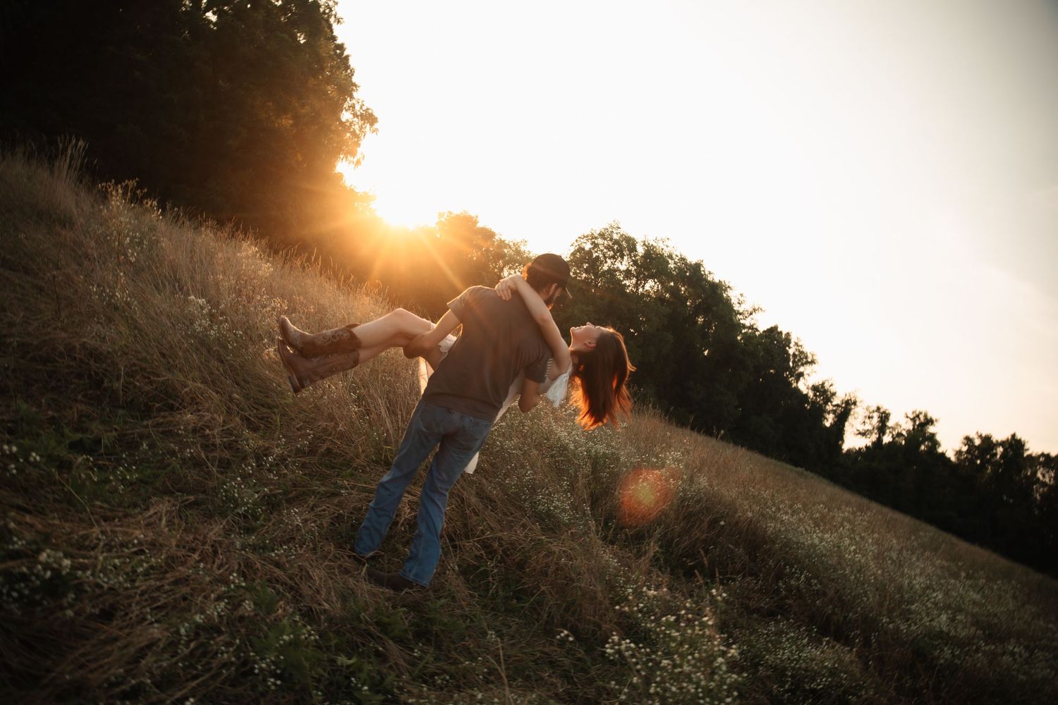 Silhouetted figures walk along a grassy hillside path during golden sunset hour with a dreamy, ethereal glow.