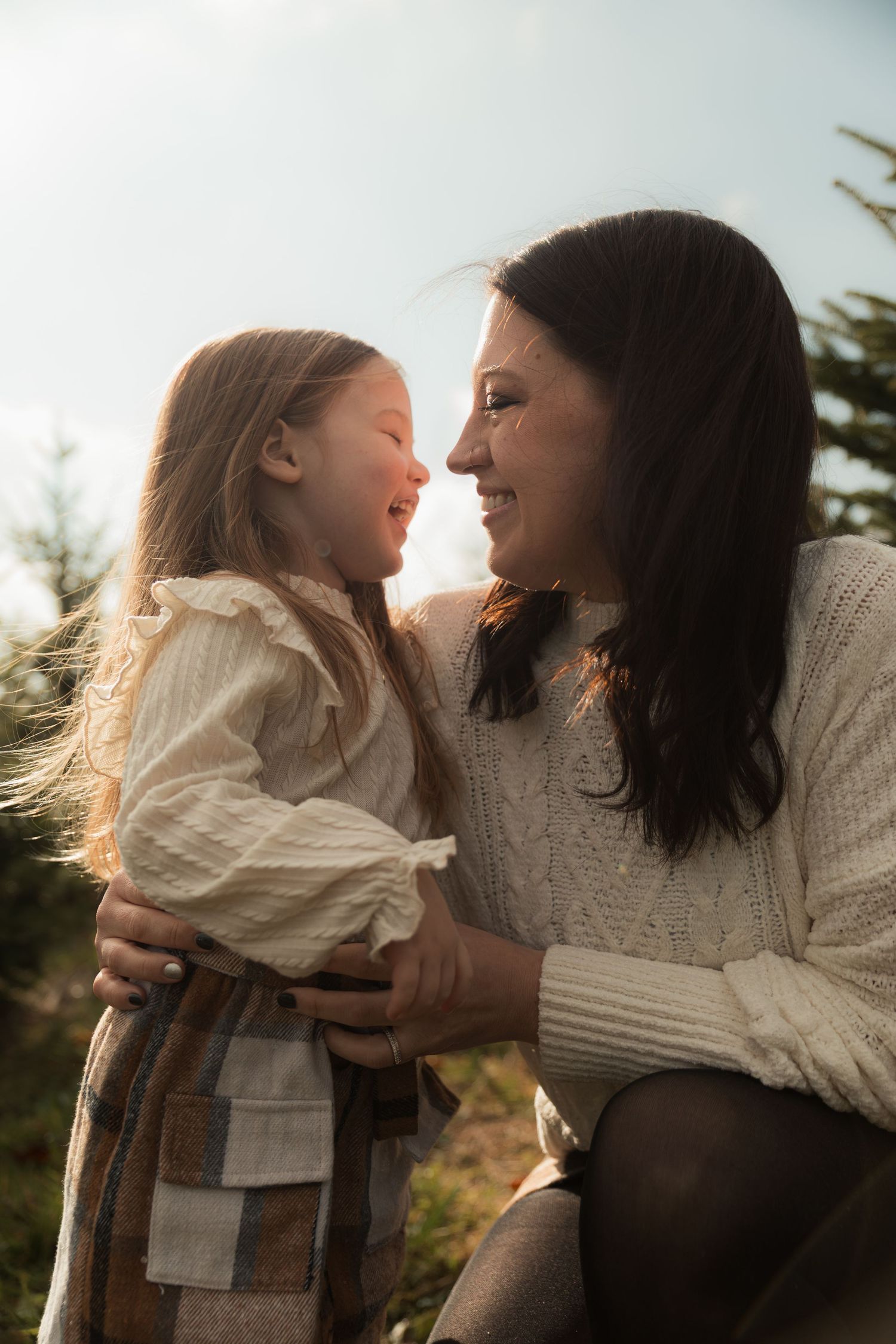 A mother and daughter share tender moments in a series of backlit outdoor photos at sunset.