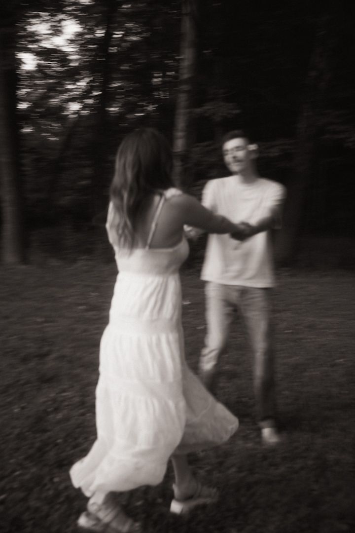 Couple dancing together in a forest, black and white photo with motion blur effect.