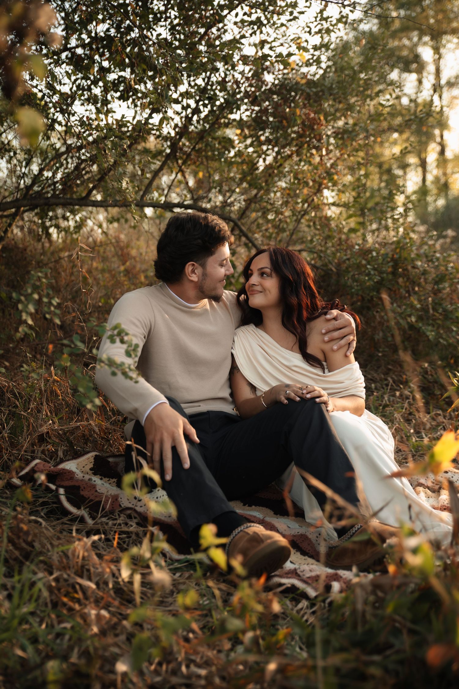 A couple shares an intimate moment while relaxing together in a natural outdoor setting during golden hour.