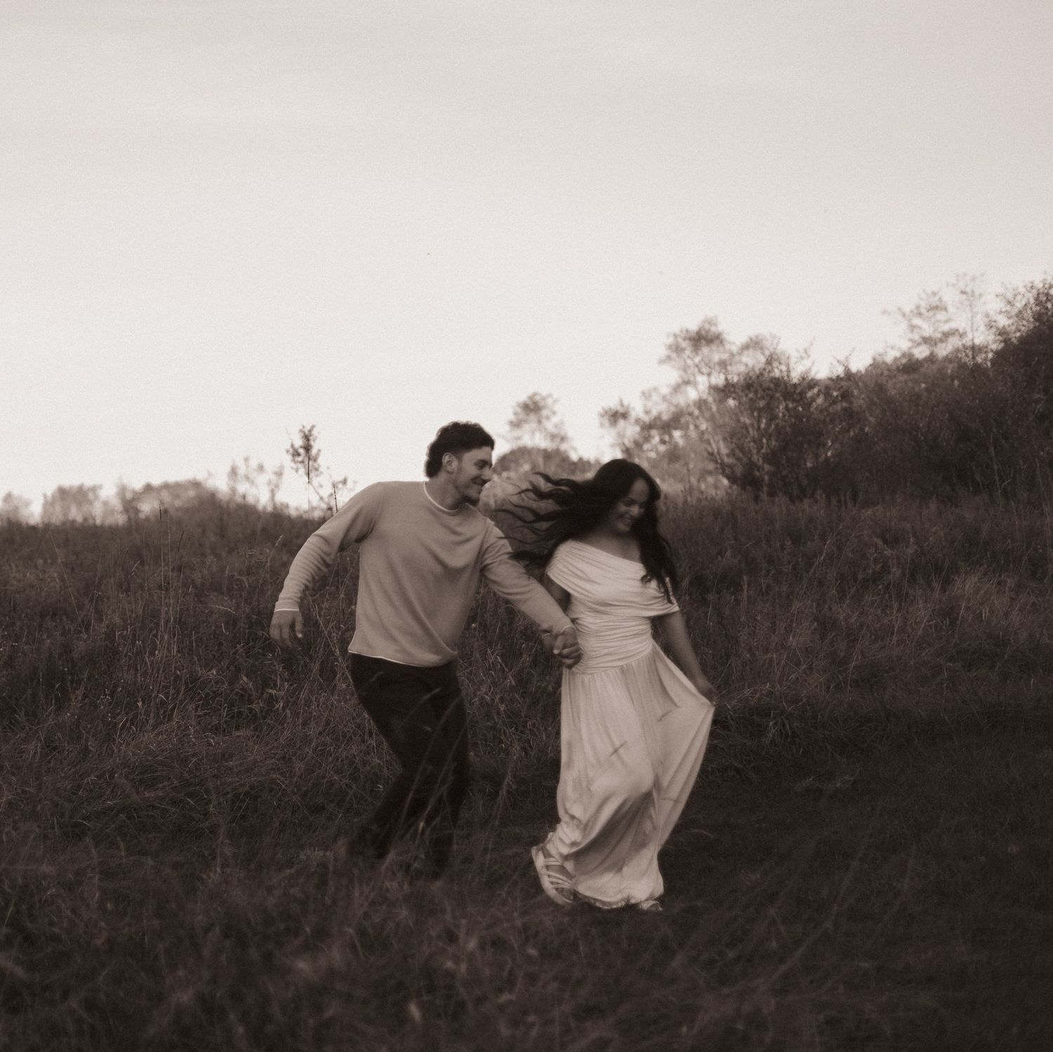 A series of black and white photographs showing a couple dancing and spinning playfully in a field at sunset.