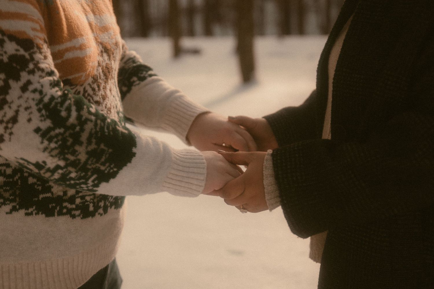A couple holding hands during an intimate wedding ceremony with soft lighting and floral decor in the background.