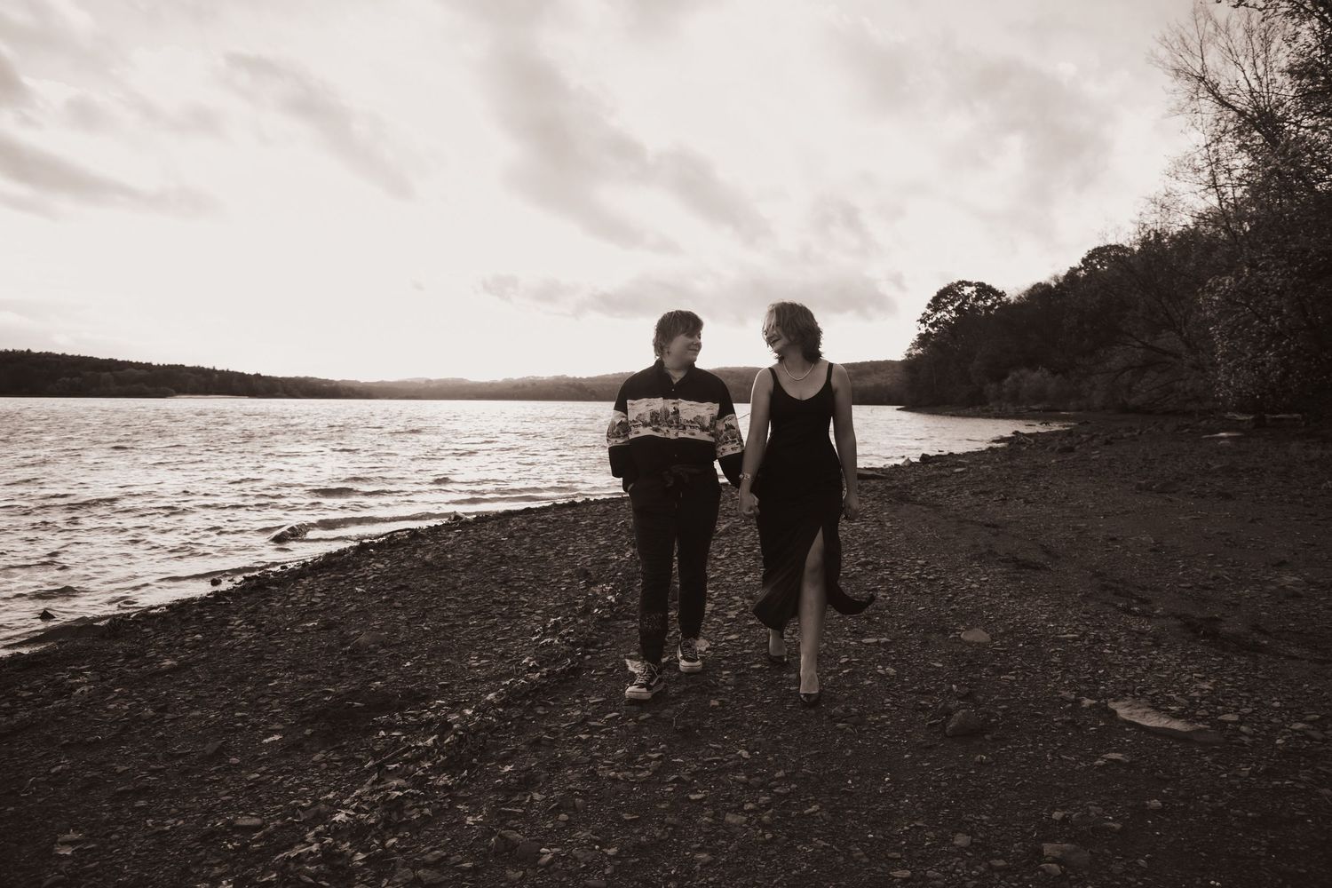 Two silhouettes walk along a misty shoreline in a series of black and white photographs.