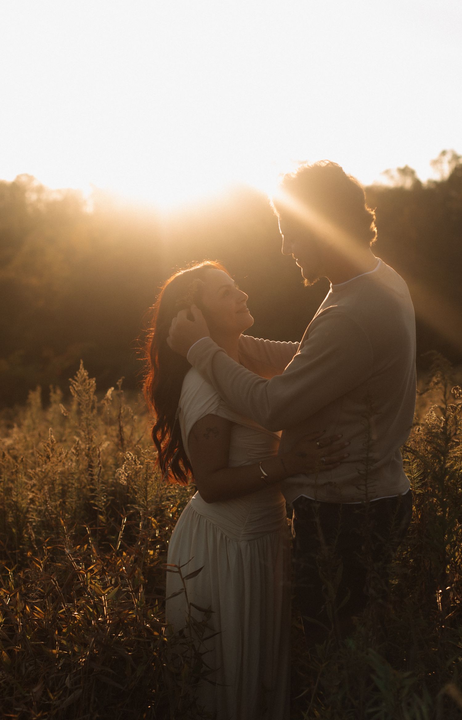 Couple embracing in golden sunset light in a wildflower field, romantic outdoor photography.