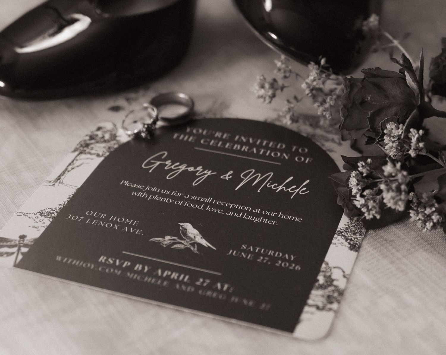 Elegant black and white wedding celebration invitation card with floral details and cursive typography.