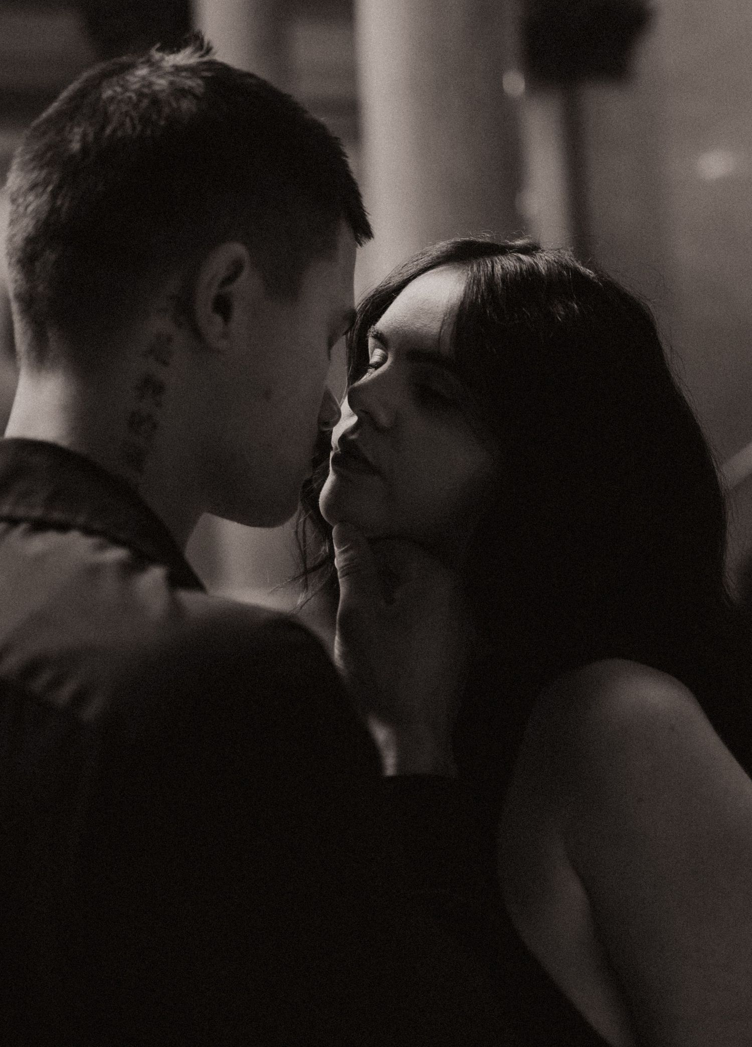 Black and white photo of a couple sharing an intimate moment, nearly kissing.