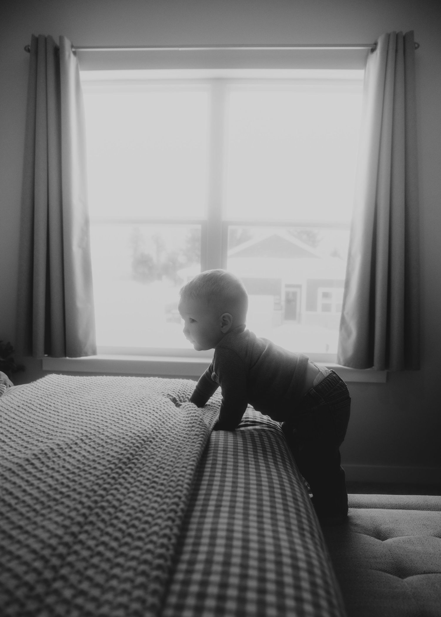 A sequence of black and white photos showing someone crawling across a bed with a checkered pattern bedspread.