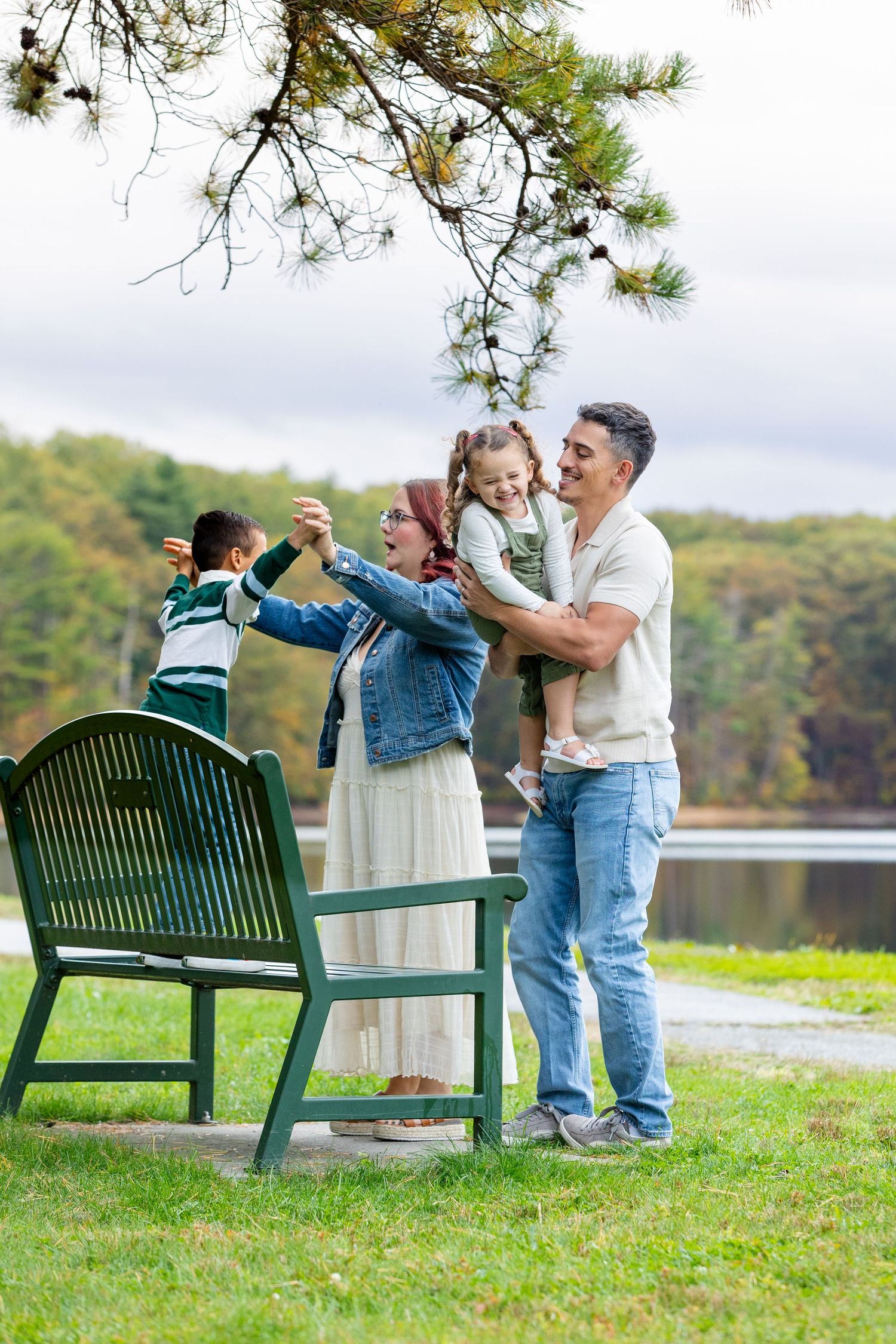 Couple dancing and embracing on grassy lawn near green park bench with autumn trees in background.