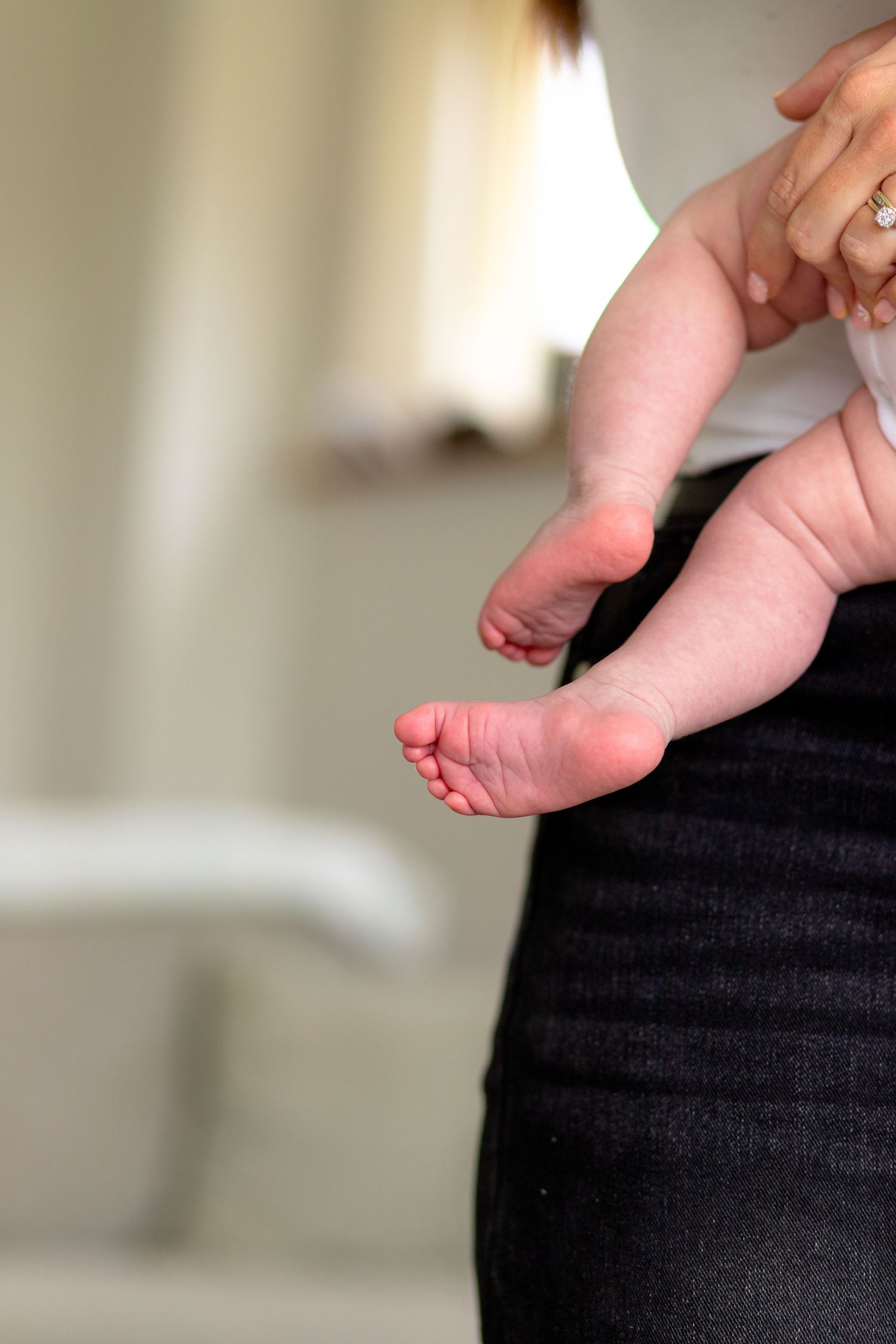 Newborn wrapped in blanket being held by mother during soft natural light photography West Yorkshire