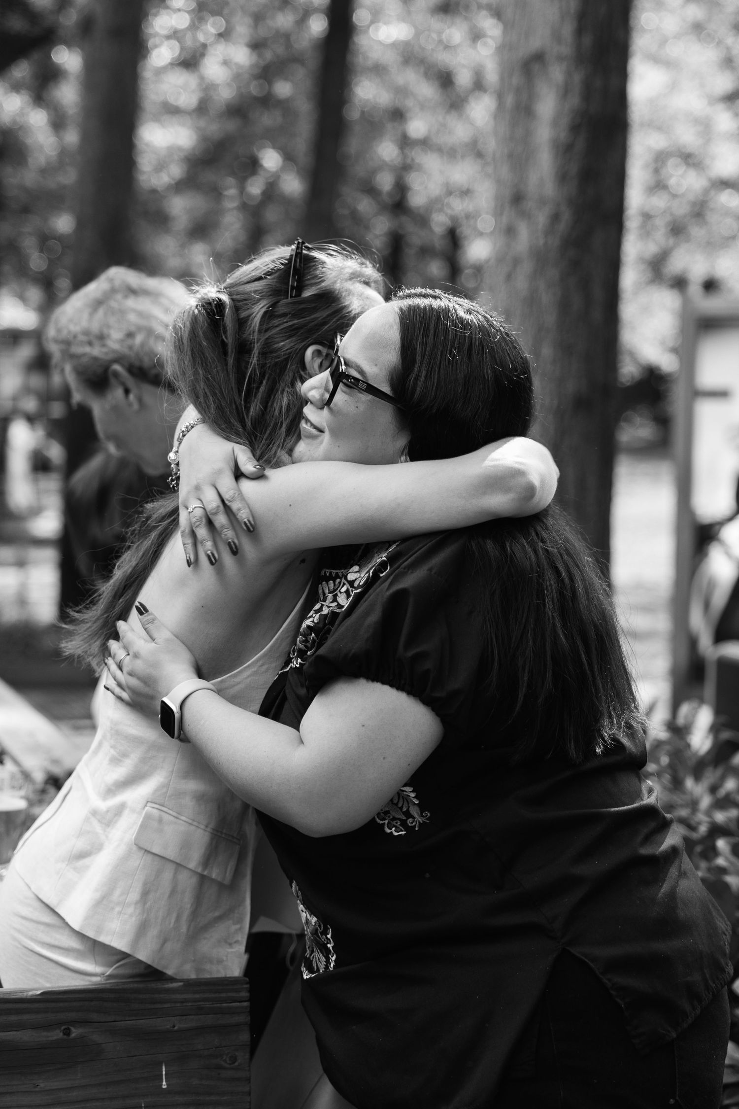 Two women sharing a warm embrace outdoors in black and white photo.