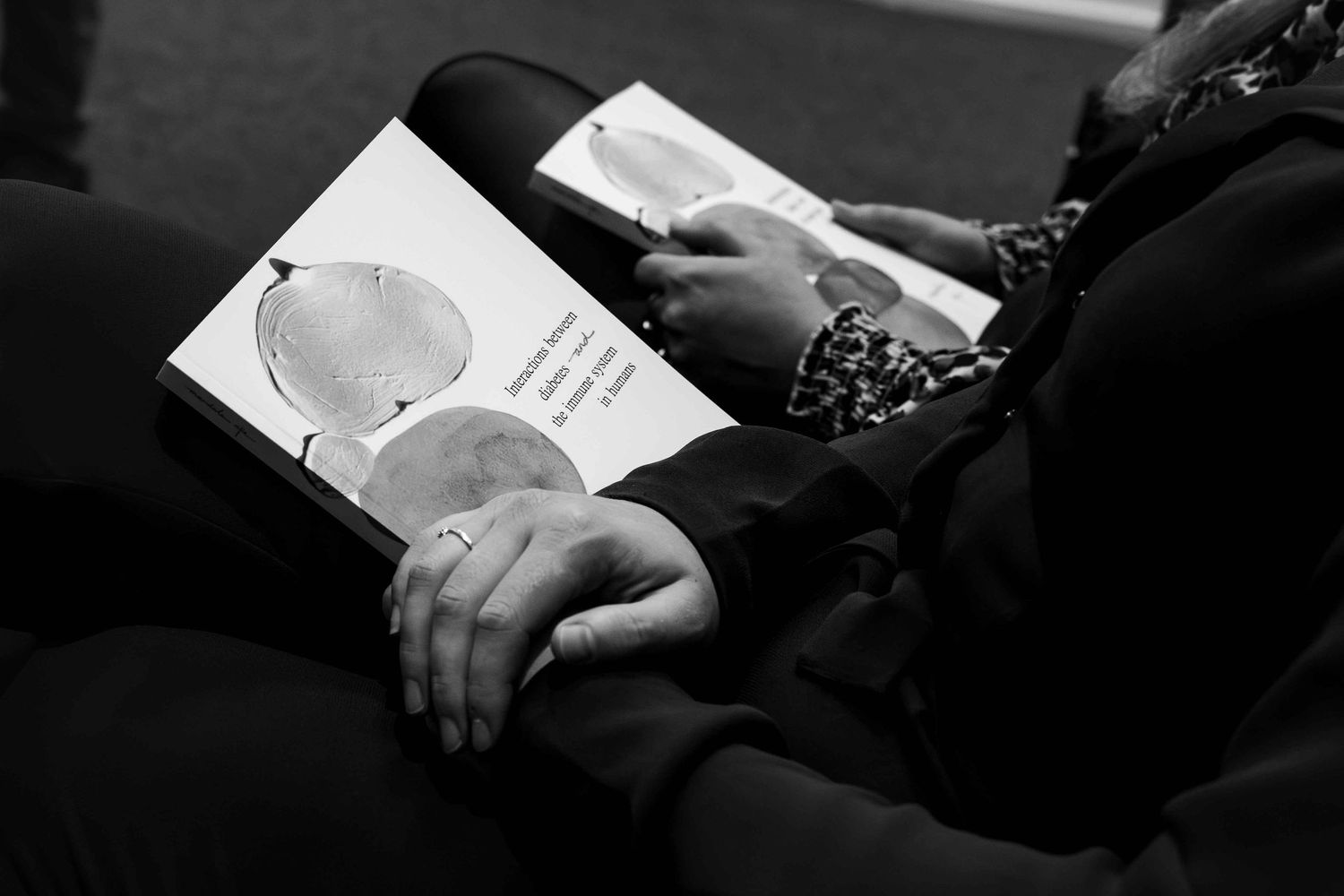Person reading a book with circular illustrations in black and white photography.