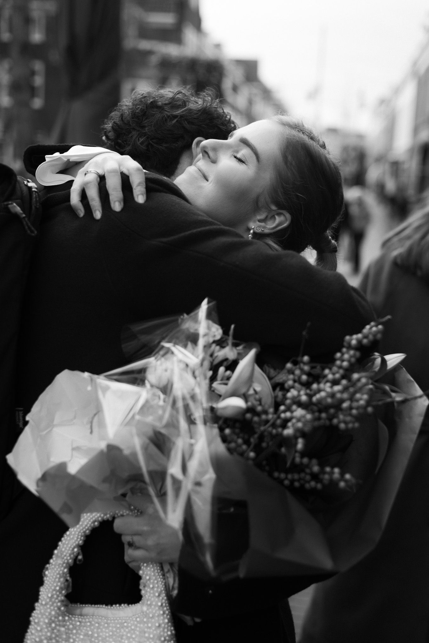 Tijdloos zwart-wit portret van een liefdevolle omhelzing op een bruiloft; focus op echte emoties en ongedwongen momenten.