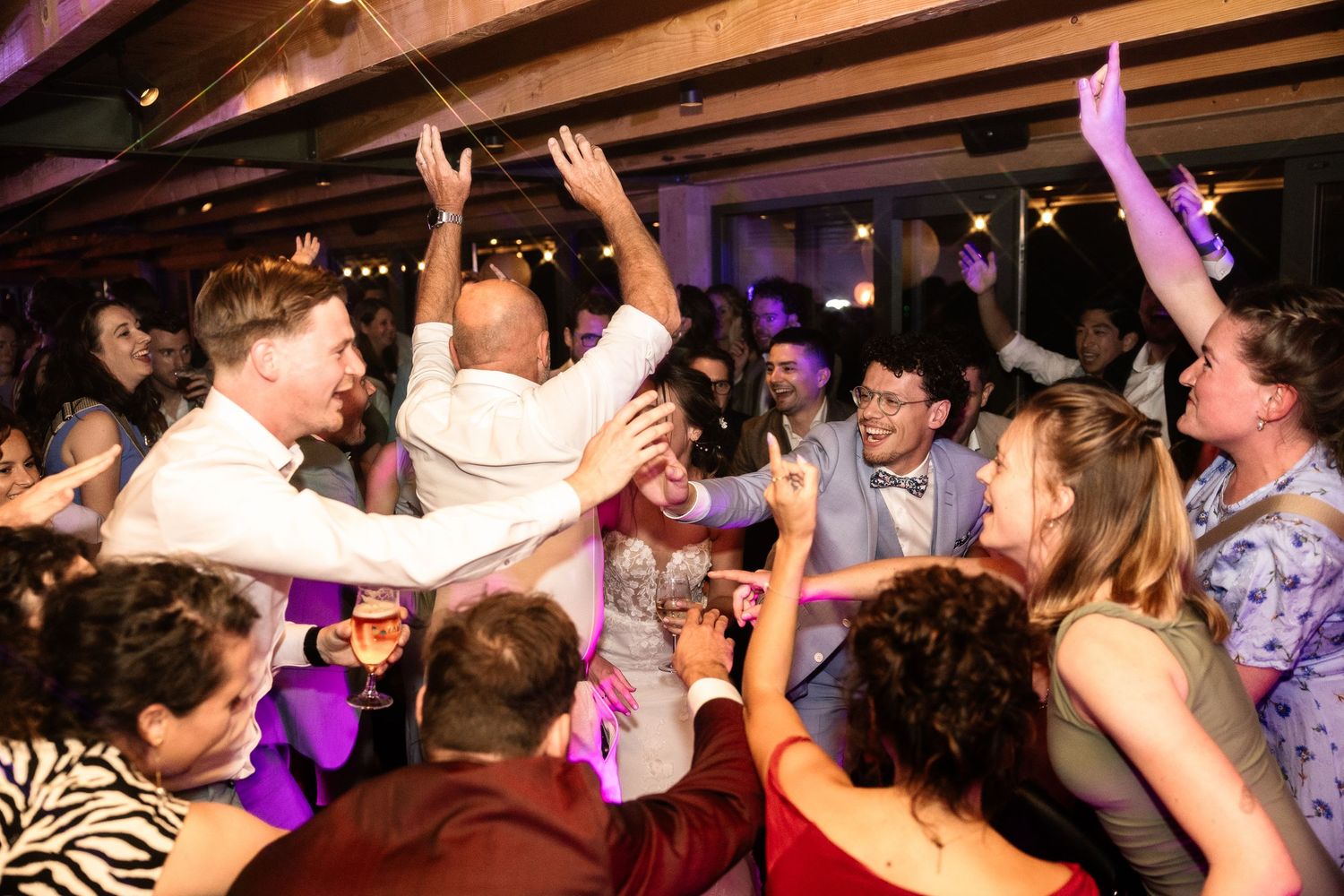 Guests dancing and celebrating joyfully at a lively wedding reception party indoors.