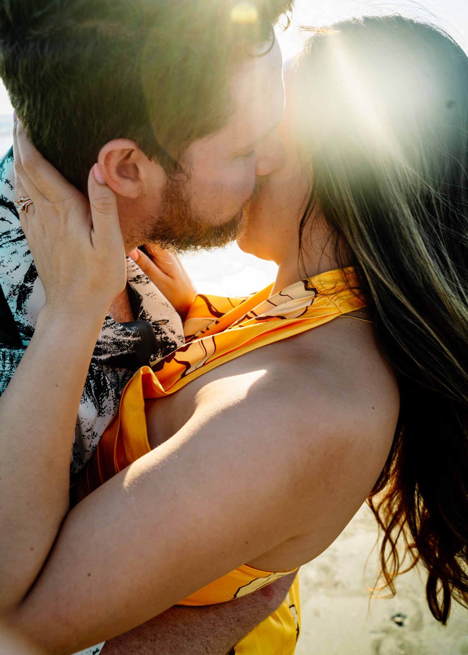 Romantic couple shares intimate moment in sunlit outdoor setting.