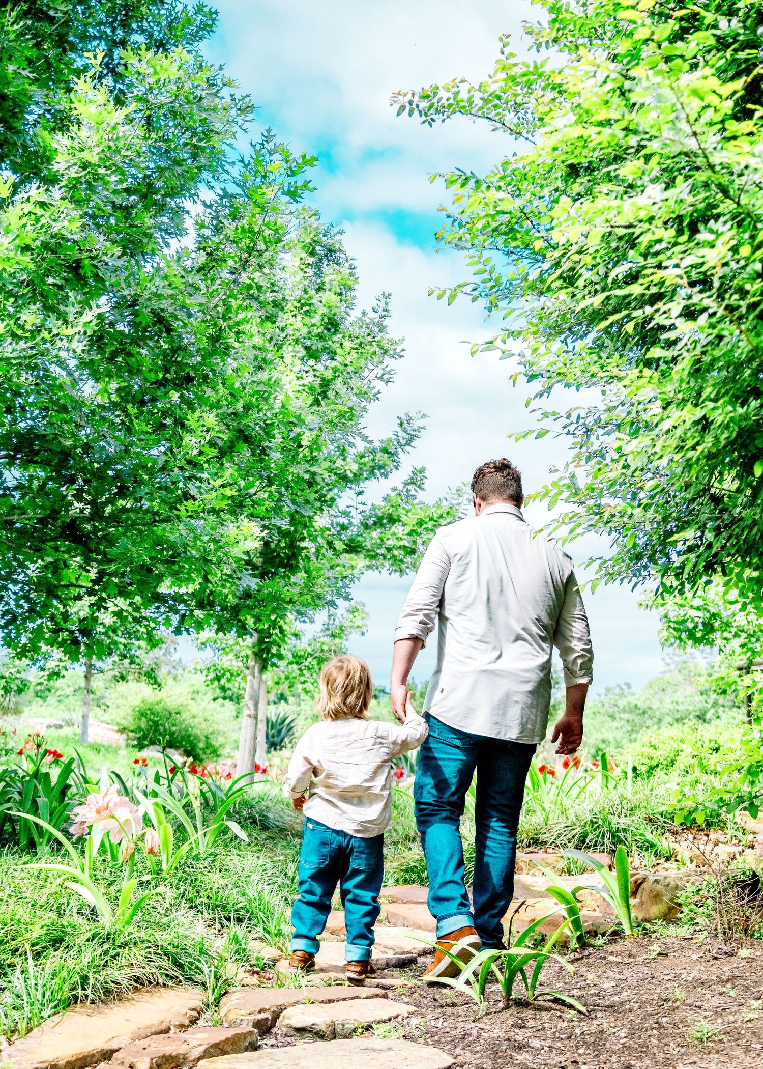 Walking together on a winding garden path surrounded by lush green trees.
