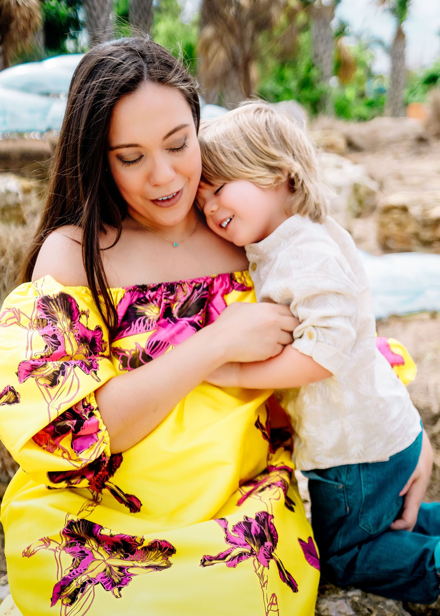 Tender embrace between parent and child against natural outdoor backdrop.