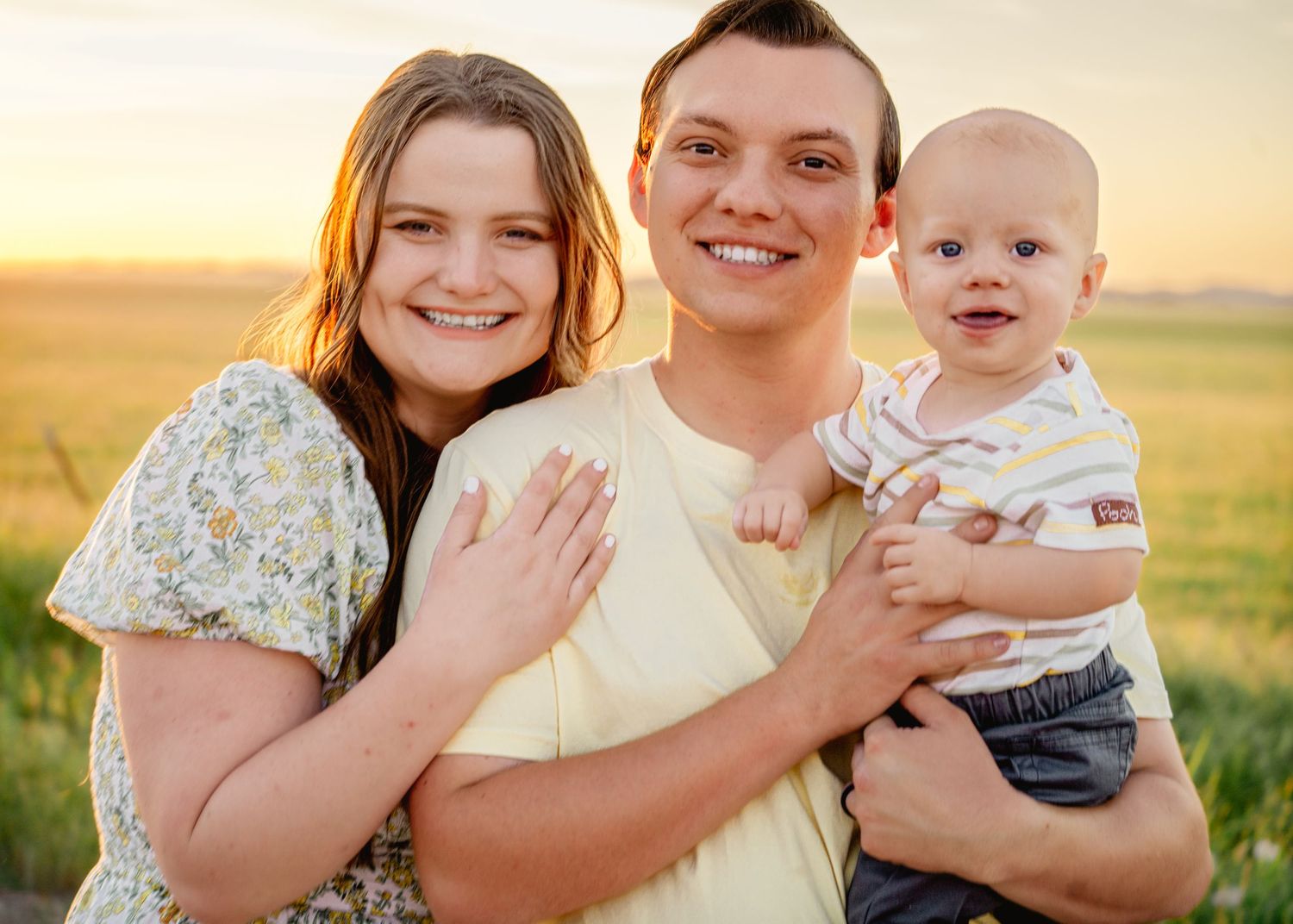 Family poses together in a golden sunset field during a professional photo session.