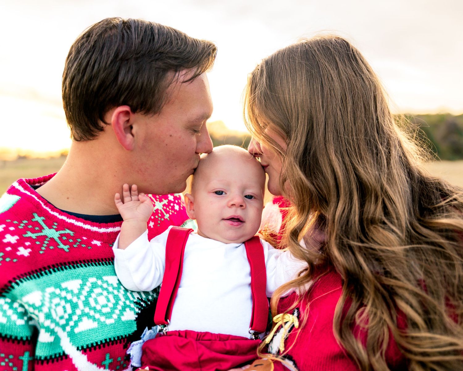 Holiday family portrait featuring matching Christmas sweaters and festive decorations.