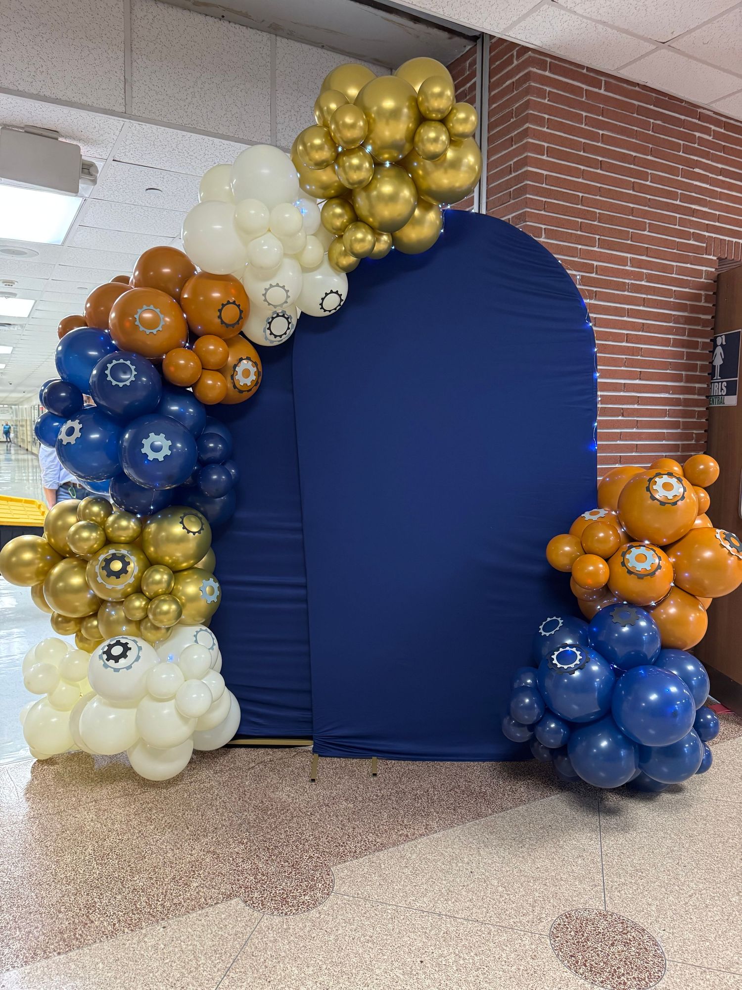 Elegant balloon arch with gold, blue, and white balloons against a navy backdrop.