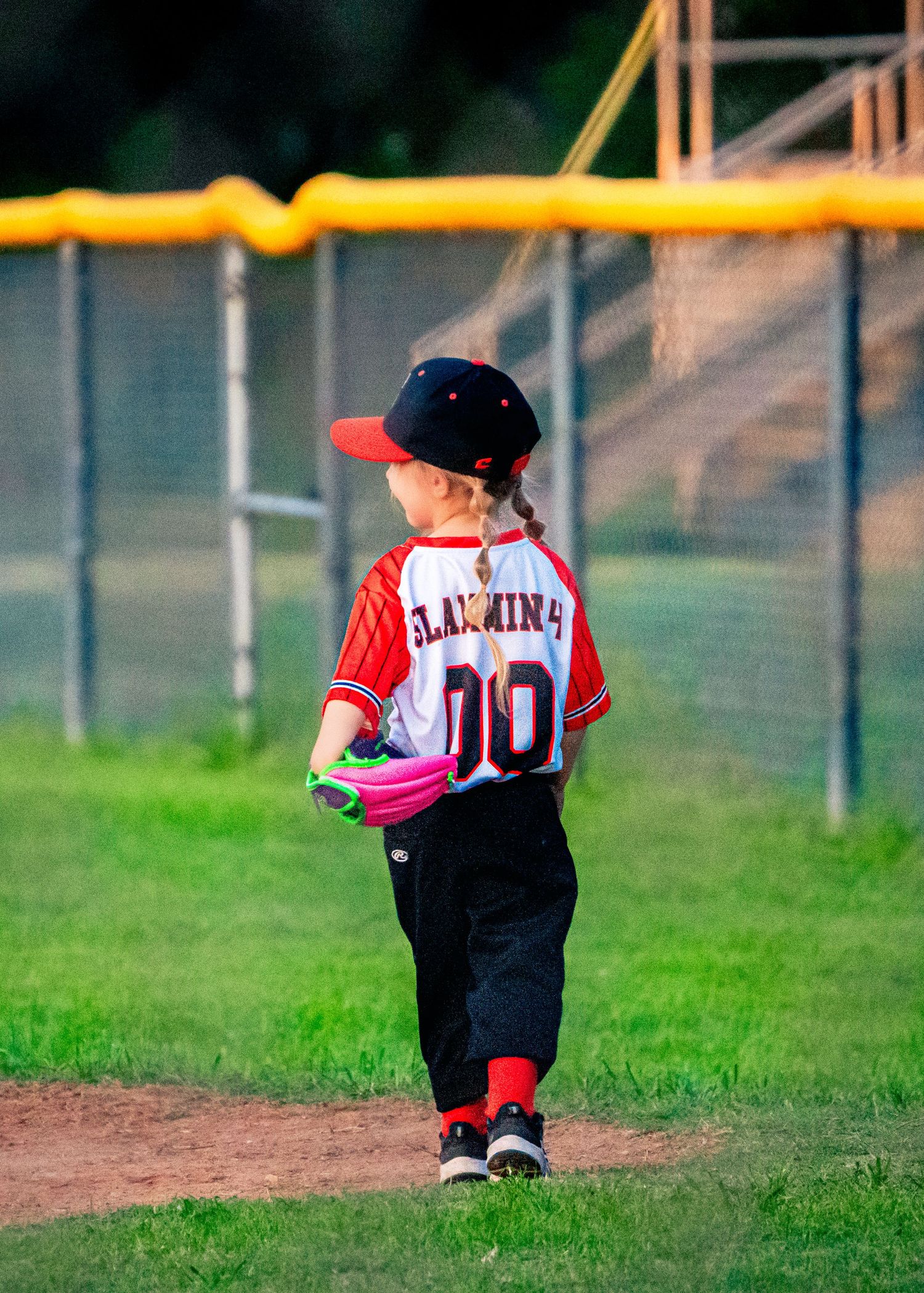 Young baseball player in red uniform standing on a baseball field.