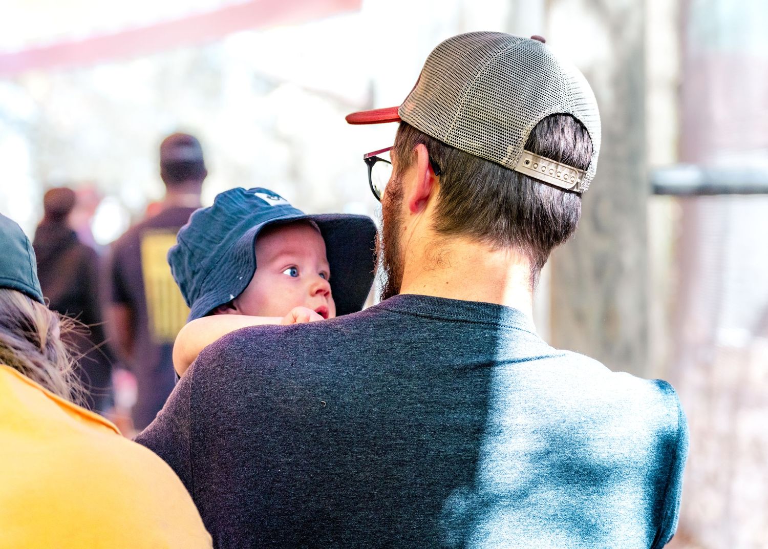 Parent and child watching an event together outdoors on a sunny afternoon.