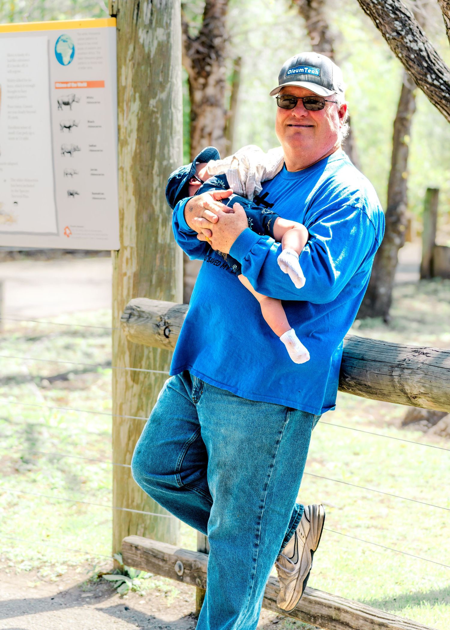 Person in blue shirt and jeans taking photos outdoors in a natural setting.