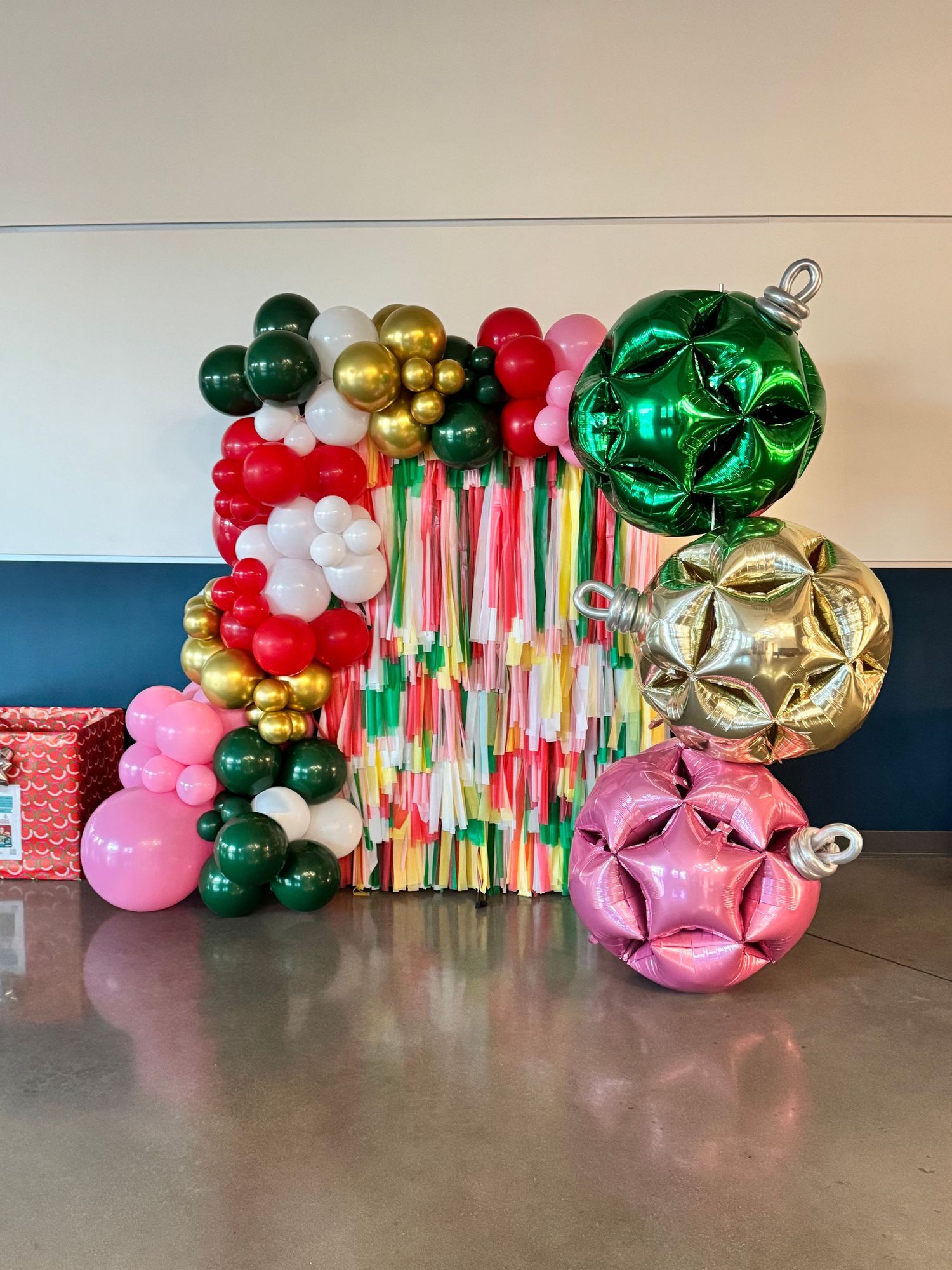 Festive balloon garland in green, gold, red and pink creates colorful party decoration display.