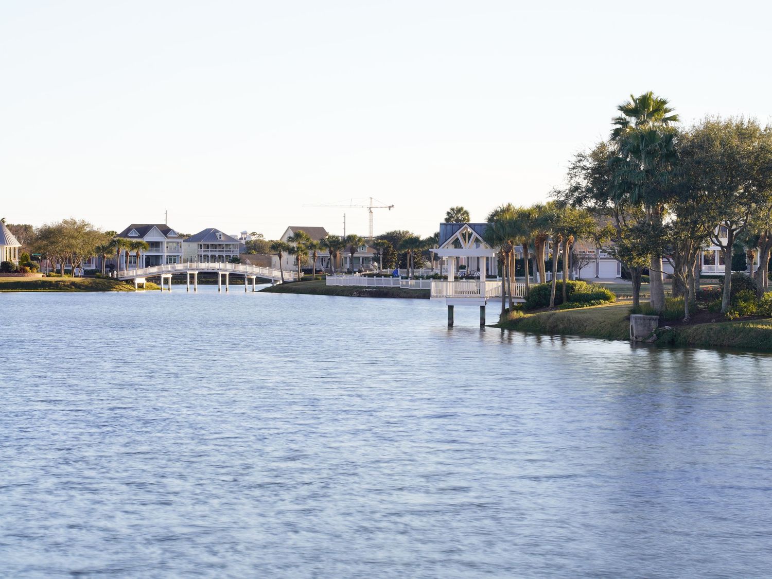 Waterfront view of luxury coastal homes with private docks and palm trees along the shoreline.