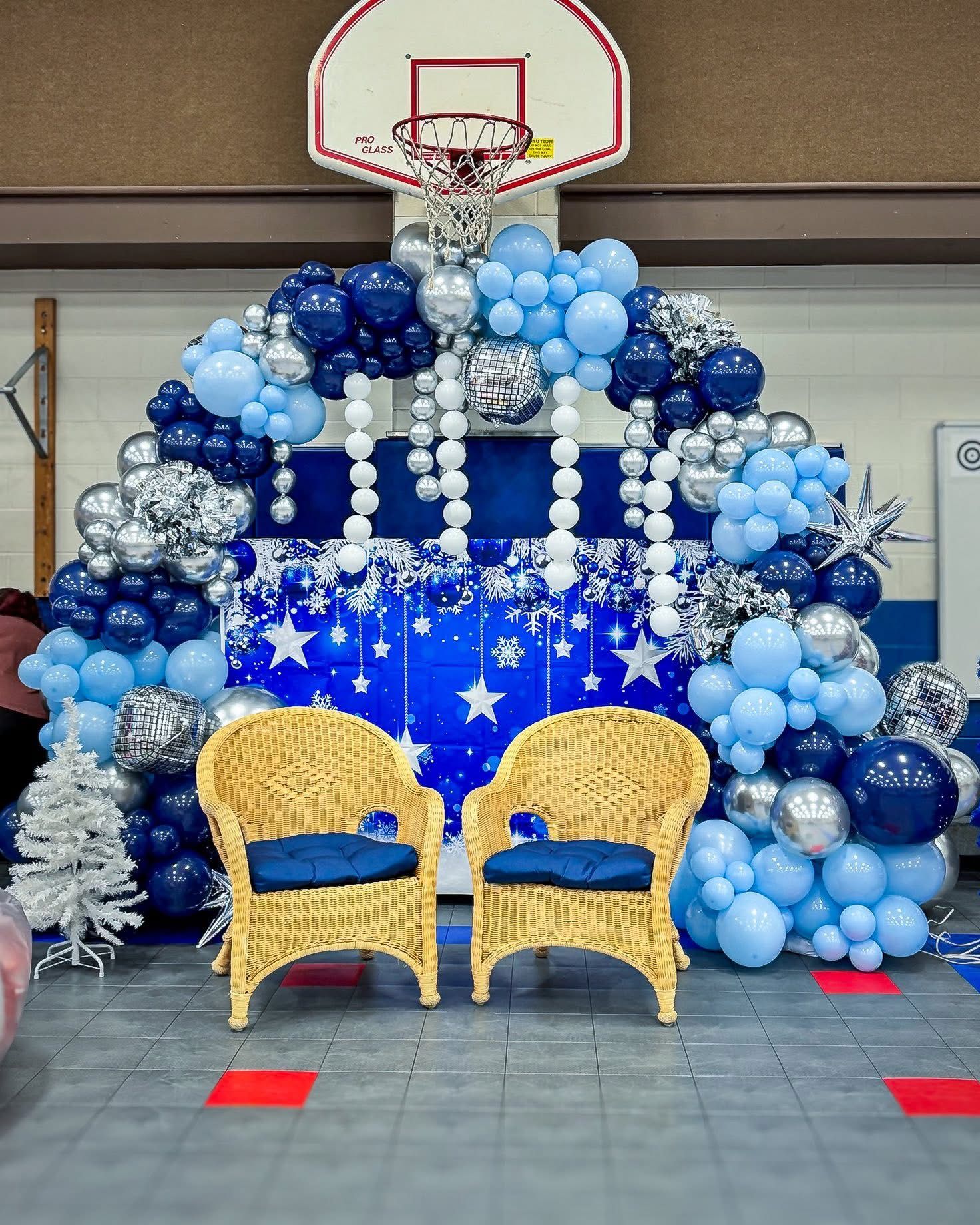 Blue and white balloon arch with gold peacock chairs for party decoration.