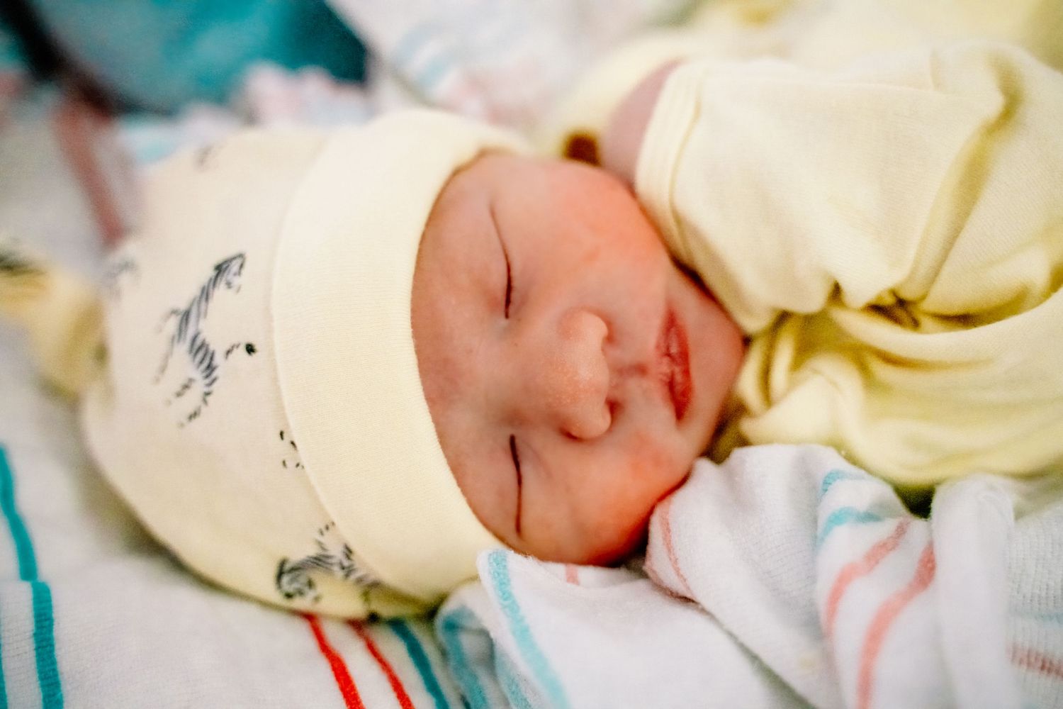 A peaceful sleeping newborn baby wrapped in a soft yellow and white blanket.
