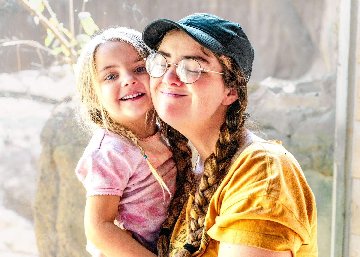 Family members share tender moments together in bright sunlit greenhouse.