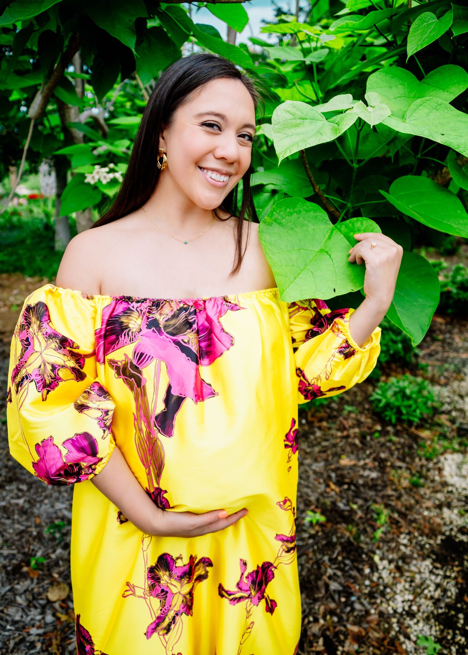 Yellow floral off-shoulder dress stands out against lush green garden backdrop.