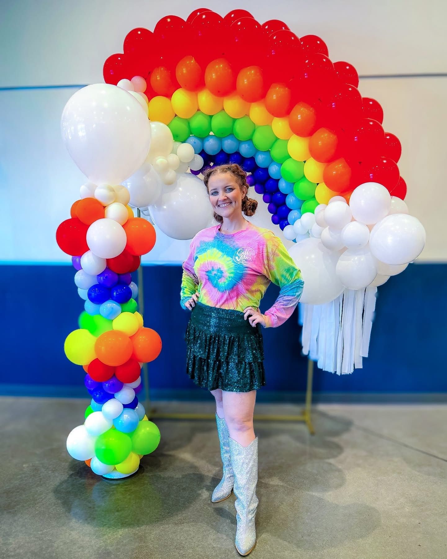 Colorful rainbow balloon arch installation in indoor event space.