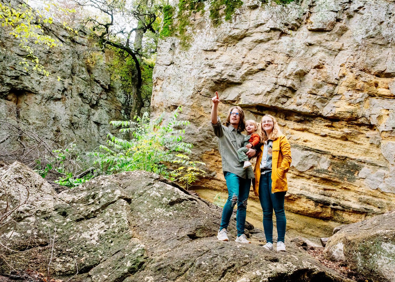 People hiking and exploring along rocky cliffs and outcroppings in a natural setting.