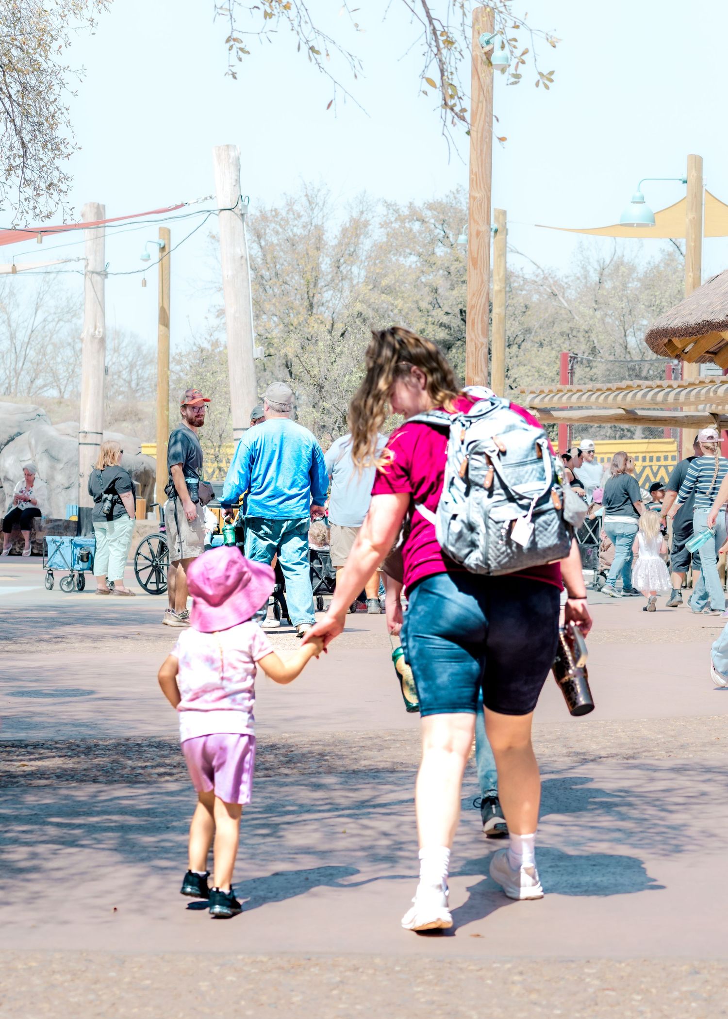 People bend down to interact with children at a busy outdoor playground.