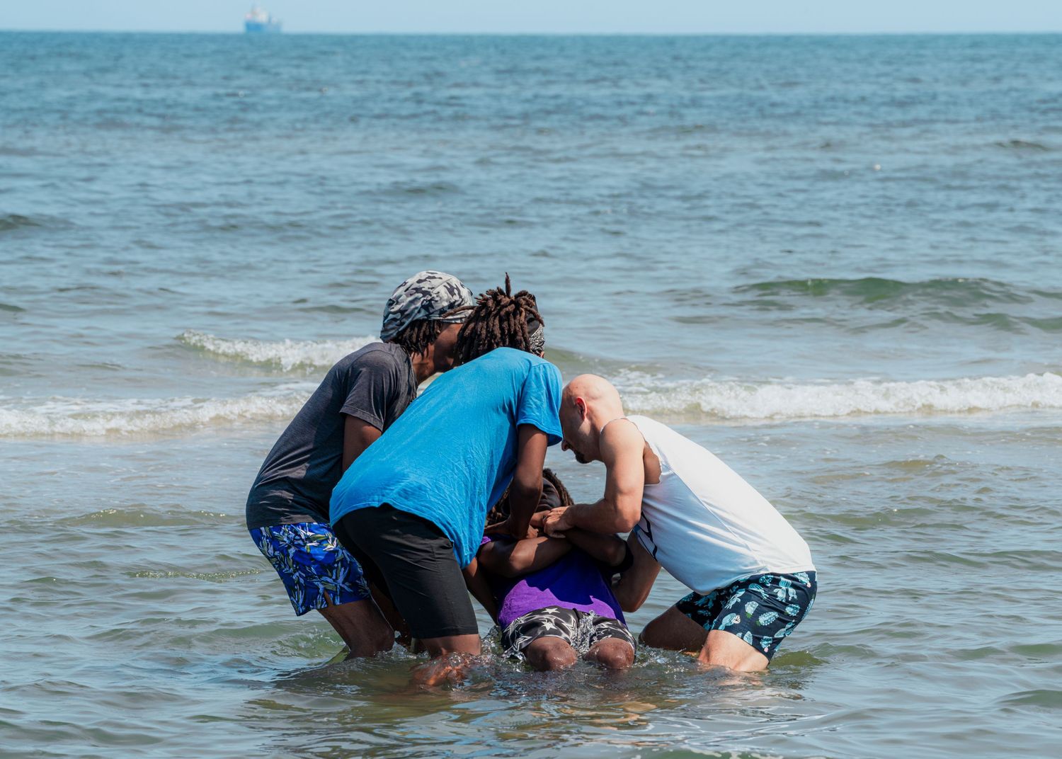 People playing and splashing in shallow ocean water.