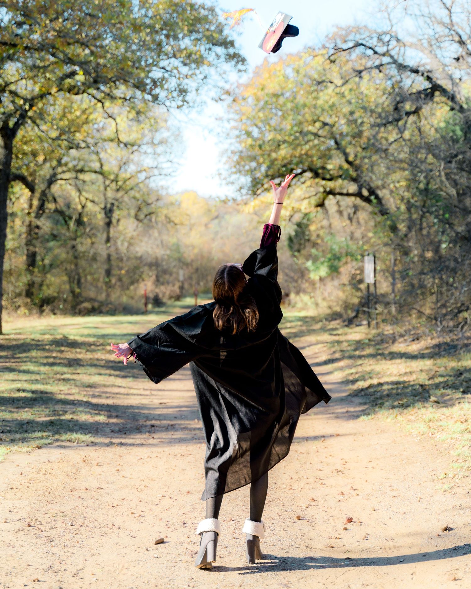 Silhouette figure in flowing black cape performing dance moves in a natural outdoor setting.