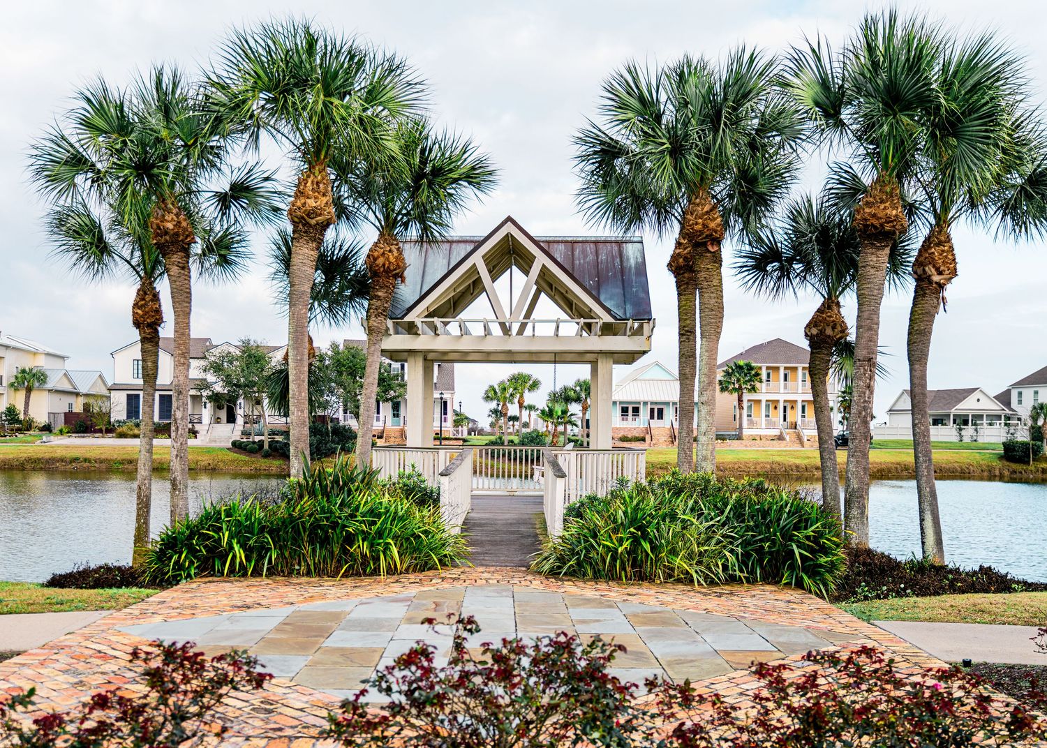 Palm tree-lined pathway leads to coastal homes with tropical landscaping.