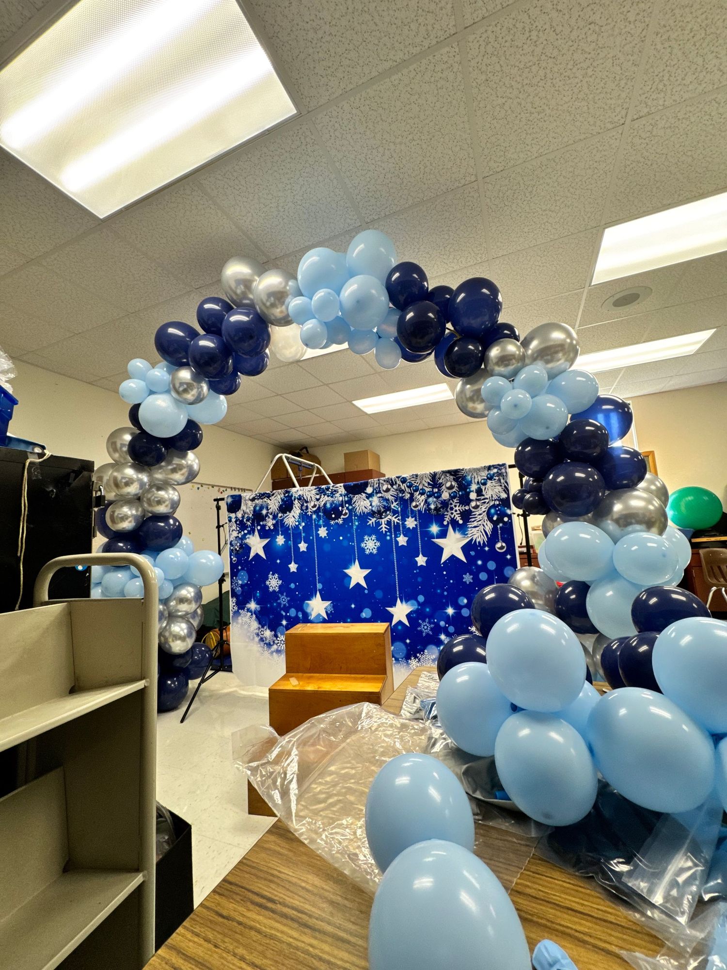 Blue and silver balloon arch decorates an office hallway with a starry backdrop.