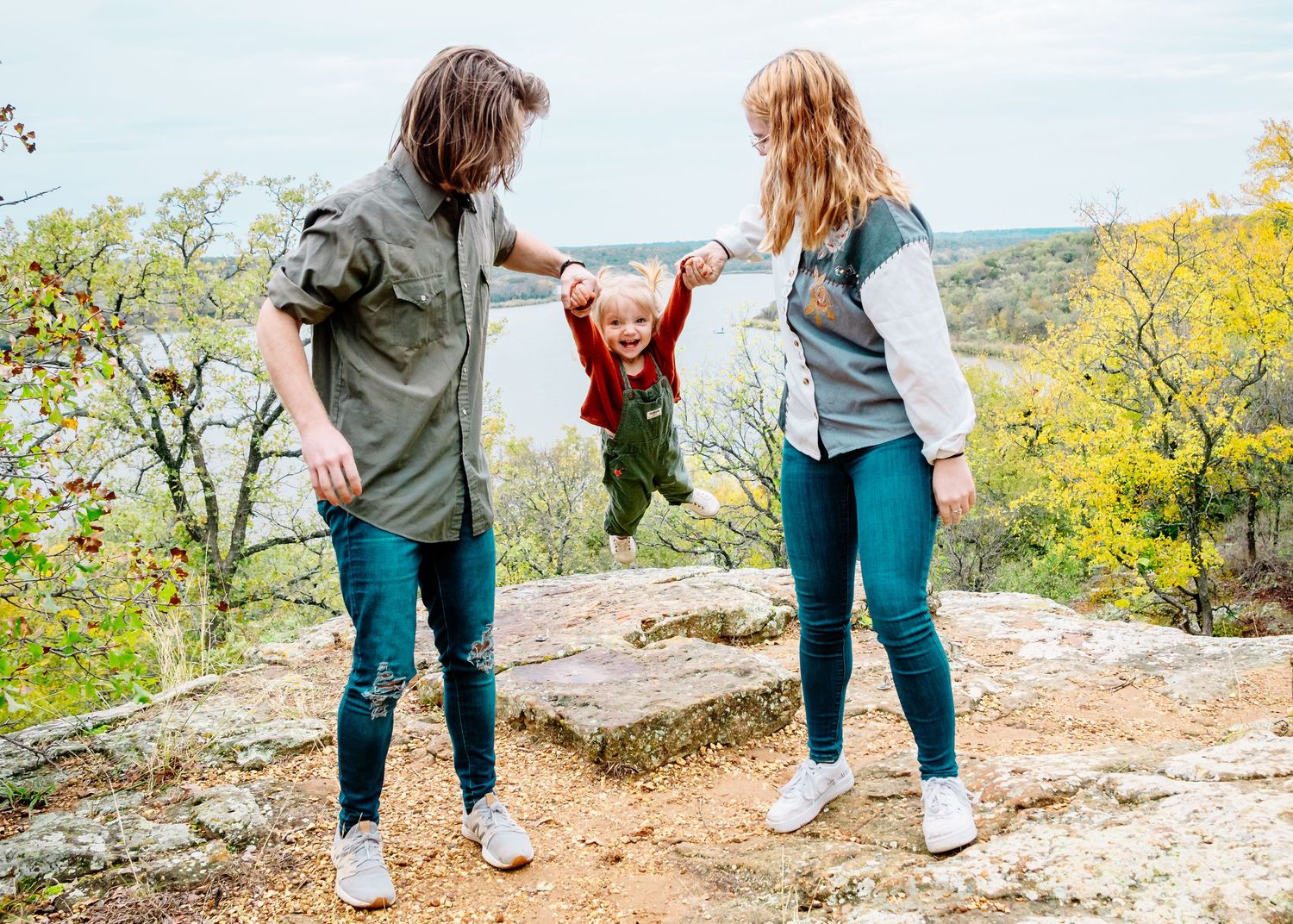People walking together on a rocky trail surrounded by autumn foliage.