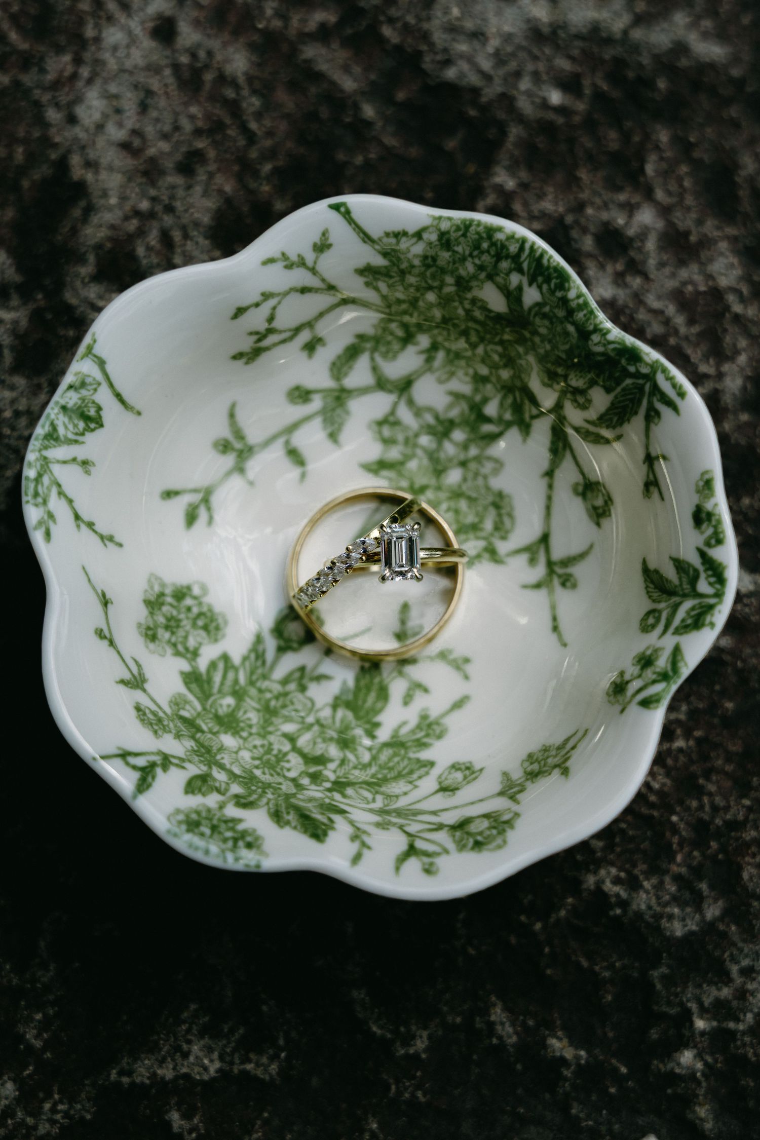 White porcelain dish with delicate green floral pattern displaying wedding rings.