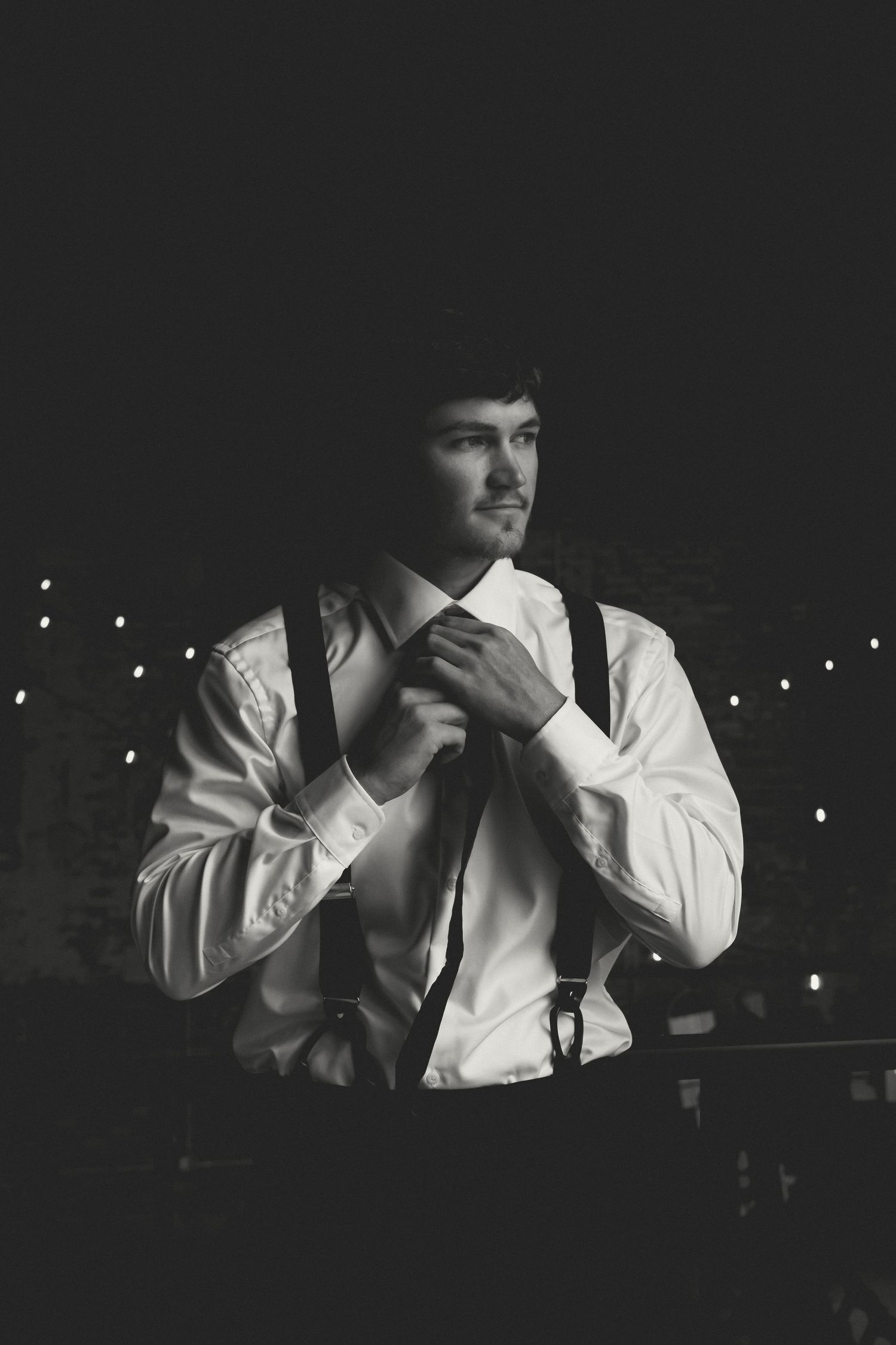 Black and white photo series of someone adjusting their tie and suspenders.