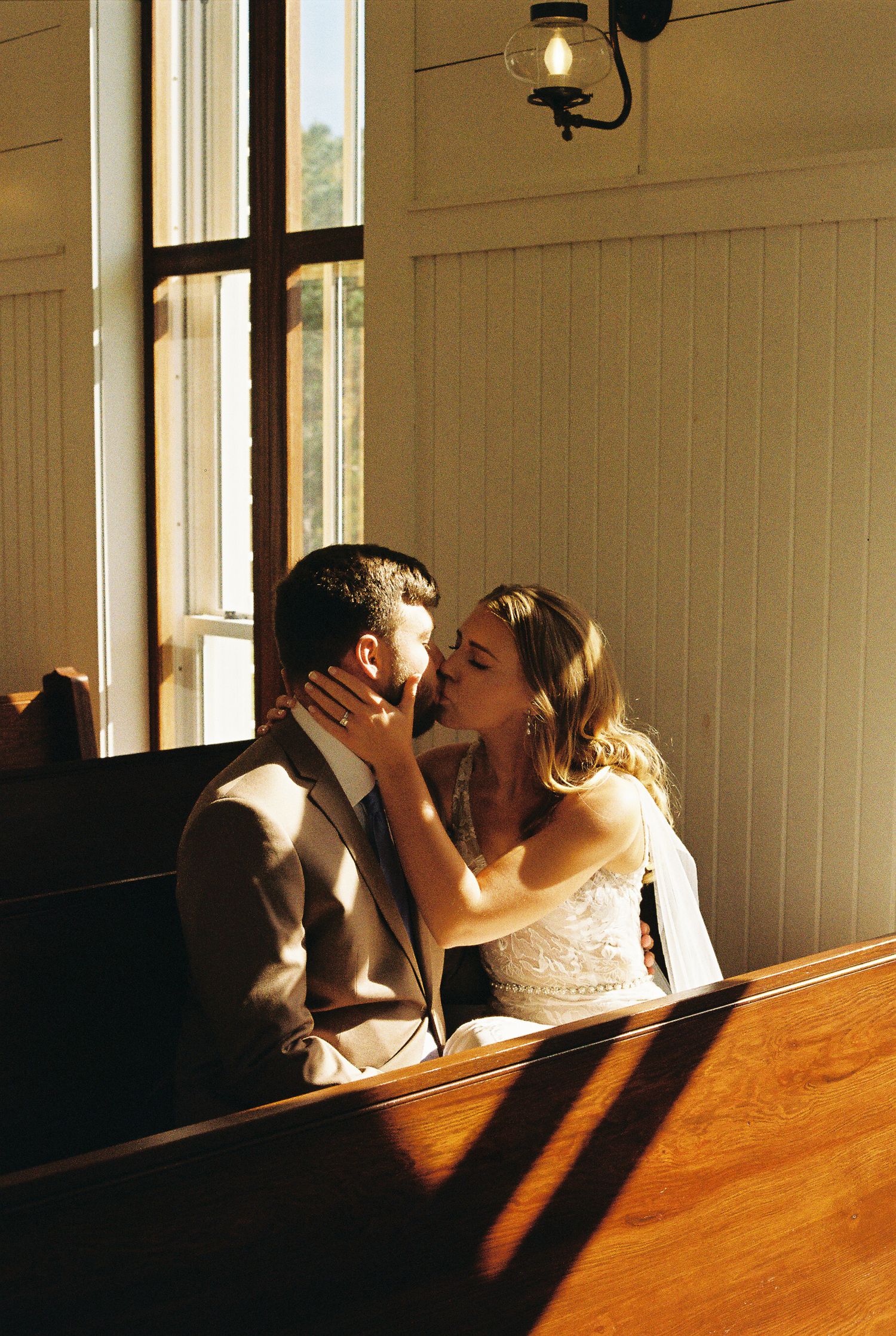A romantic moment captured in sunlit room with wooden interior.